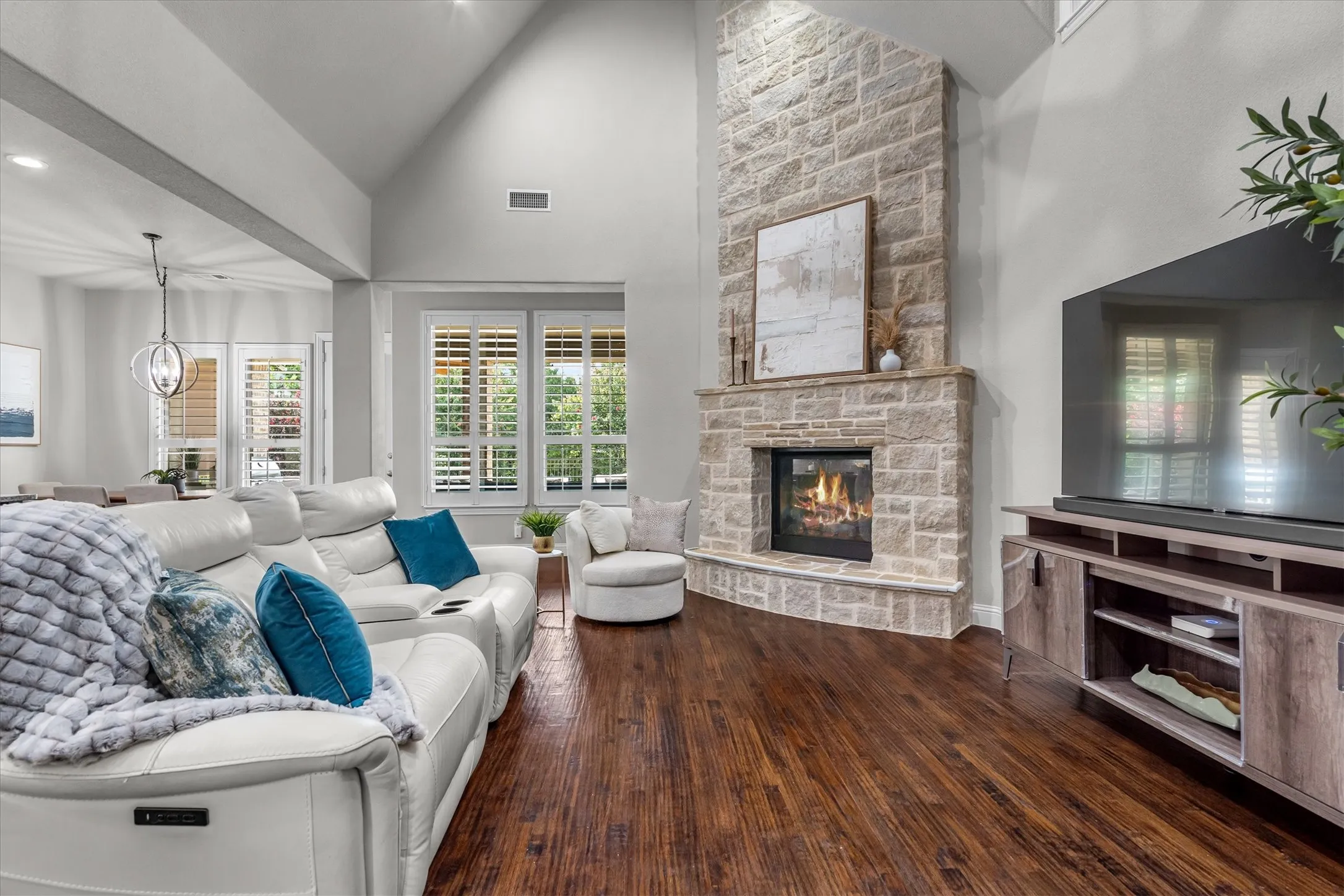 Vaulted ceilings and a floor-to-ceiling stone fireplace anchor this bright, open living space with walls of windows.