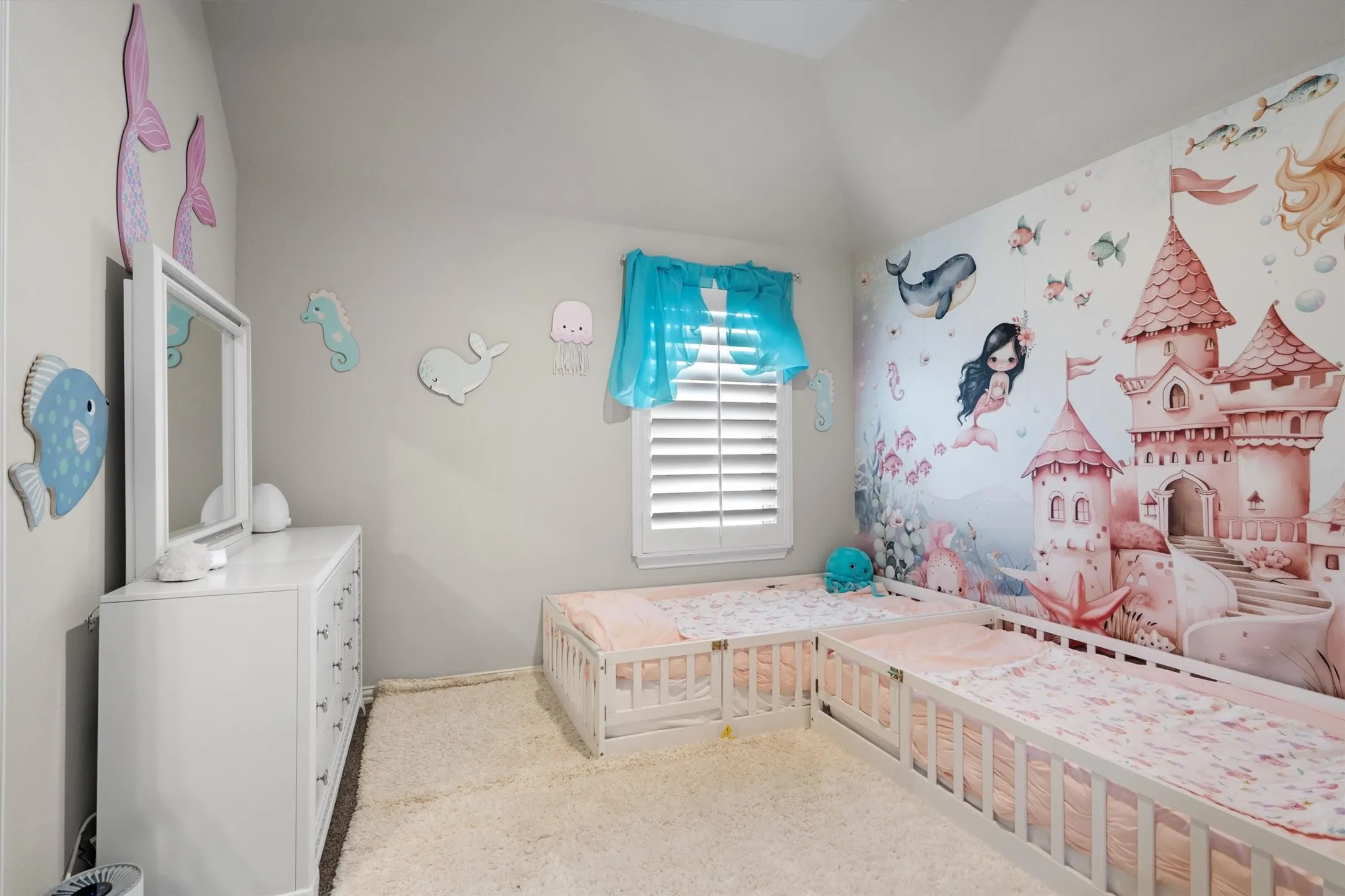 A playful, light-filled bedroom with plantation shutters and a decorative accent wall.