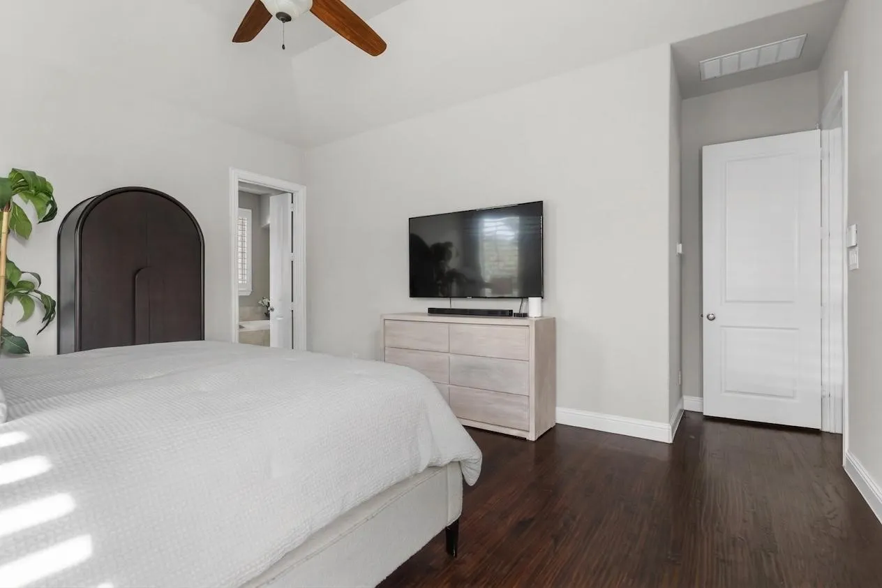 Generous proportions and warm hardwood flooring continue through this restful primary bedroom.