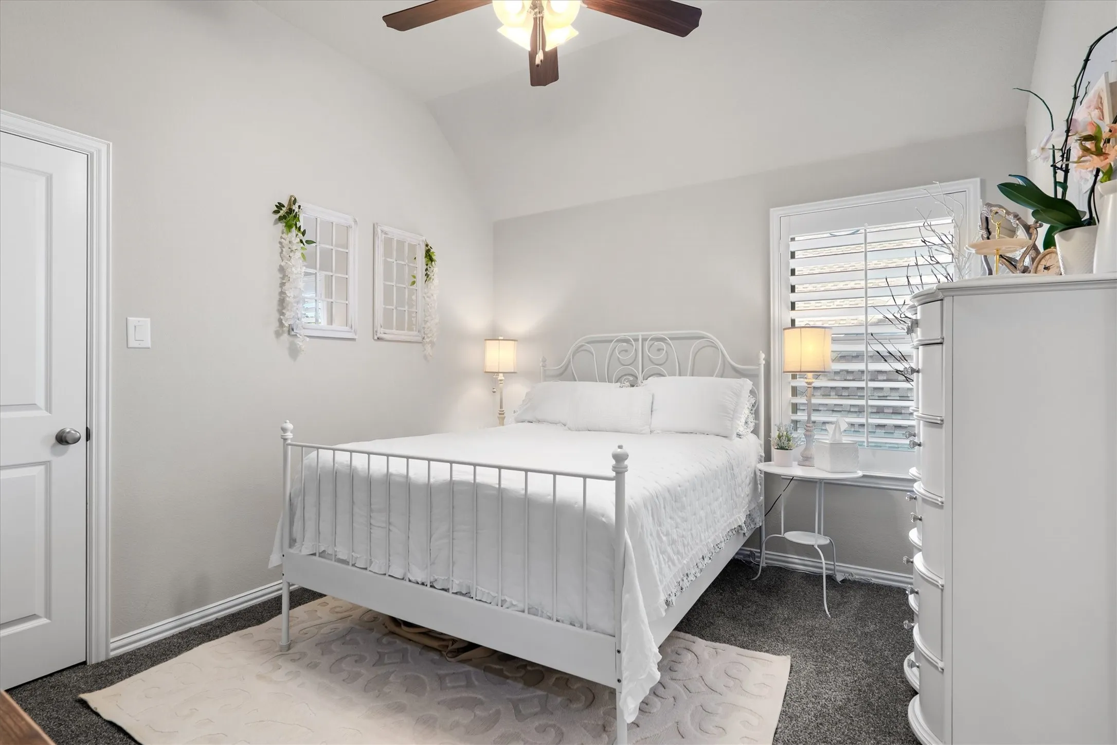 A charming bedroom with classic white iron bed, plantation shutters, and soft natural light.