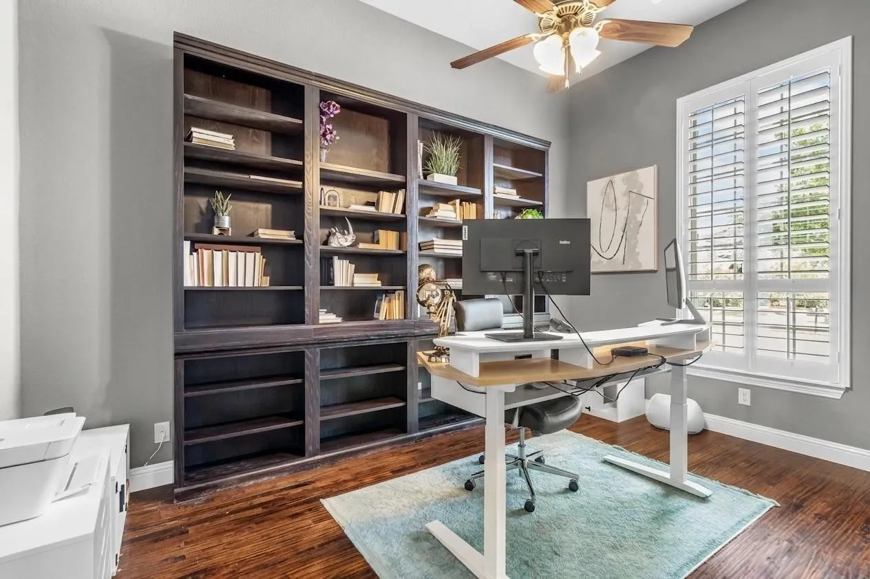 A dedicated study with floor-to-ceiling custom built-in bookshelves, plantation shutters, and hardwood flooring.