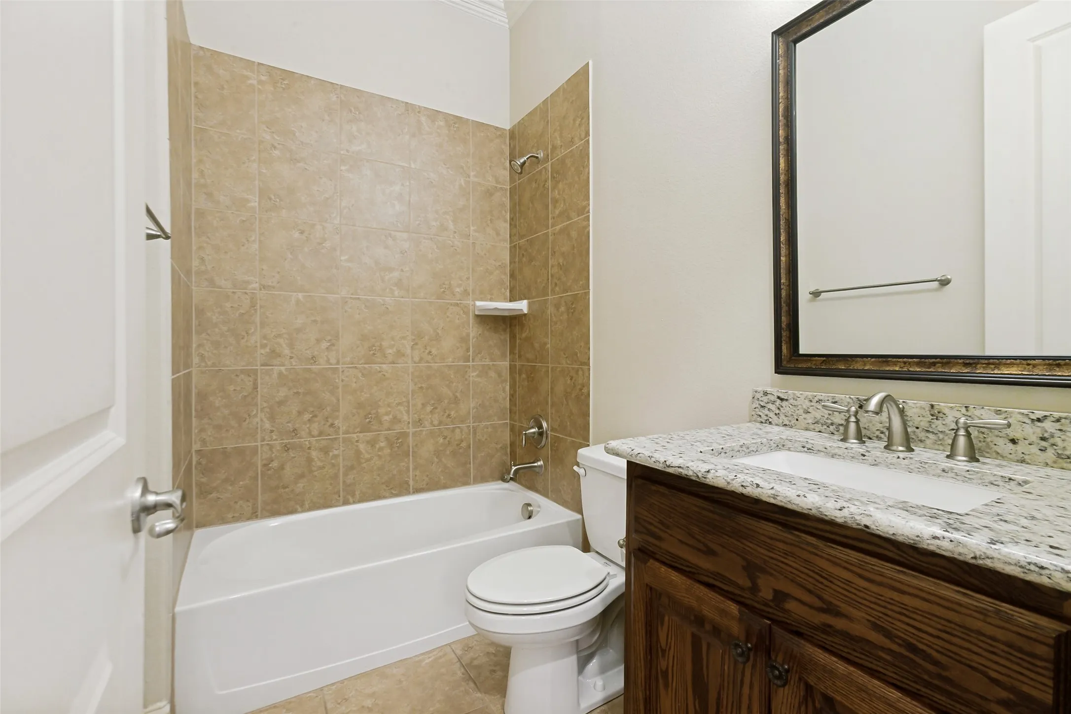 Bathroom featuring a tub/shower combination with tile surround, wood-finish vanity with stone countertop, and an undermount sink