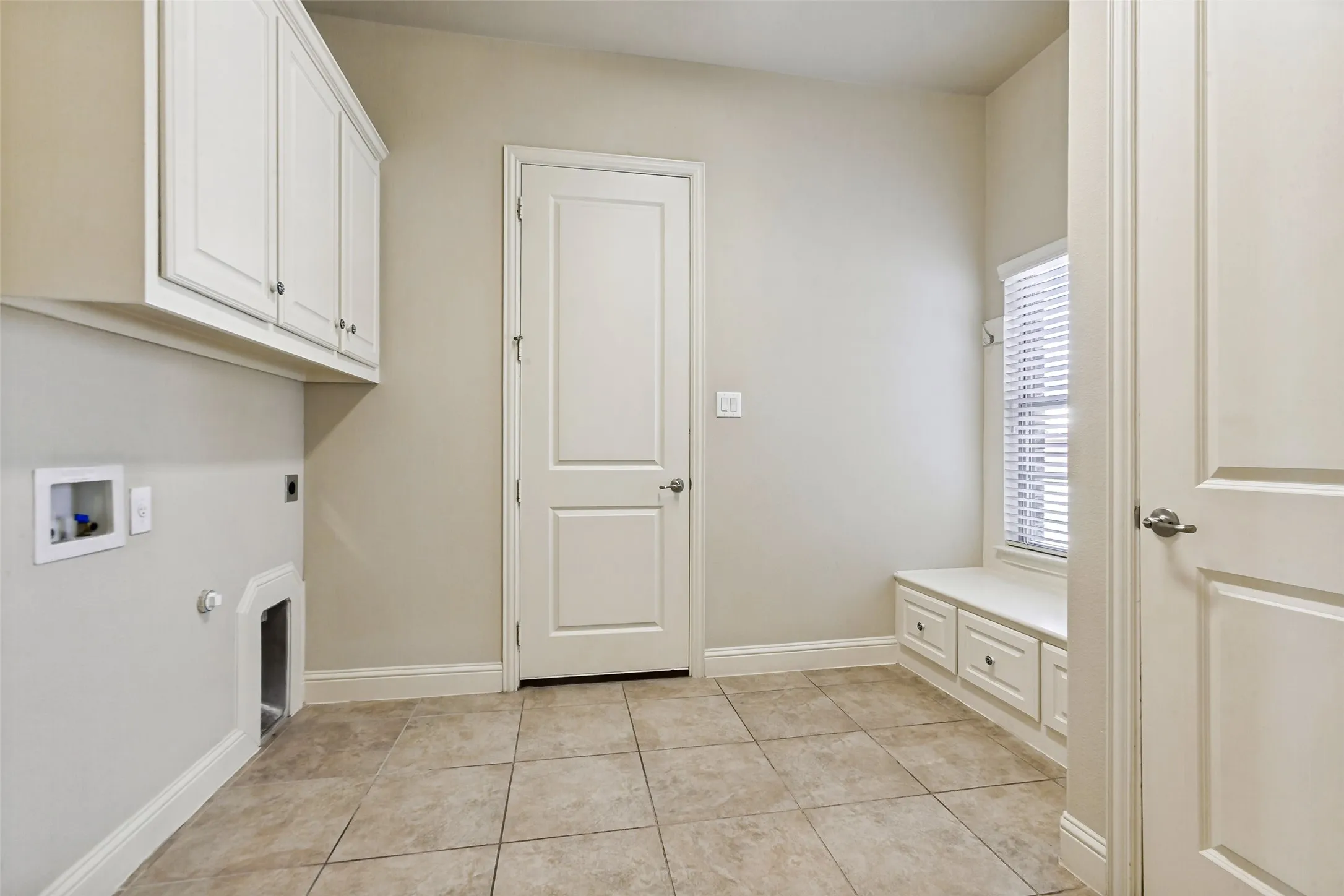 Built-in cabinetry, tiled flooring, window with blinds, built-in window bench, and an interior door