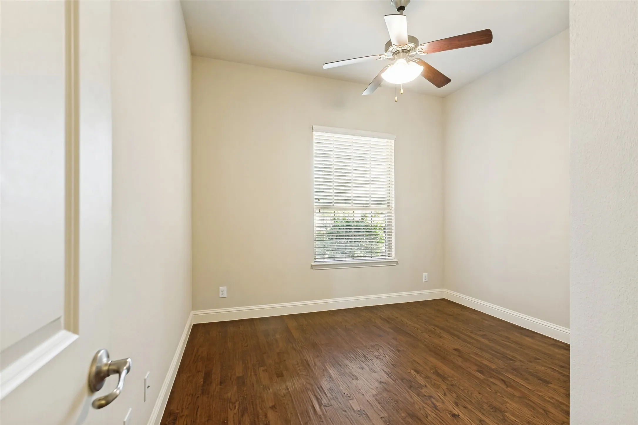 Wood-finish flooring, single window with blinds, ceiling fan with light fixture, and neutral wall tones