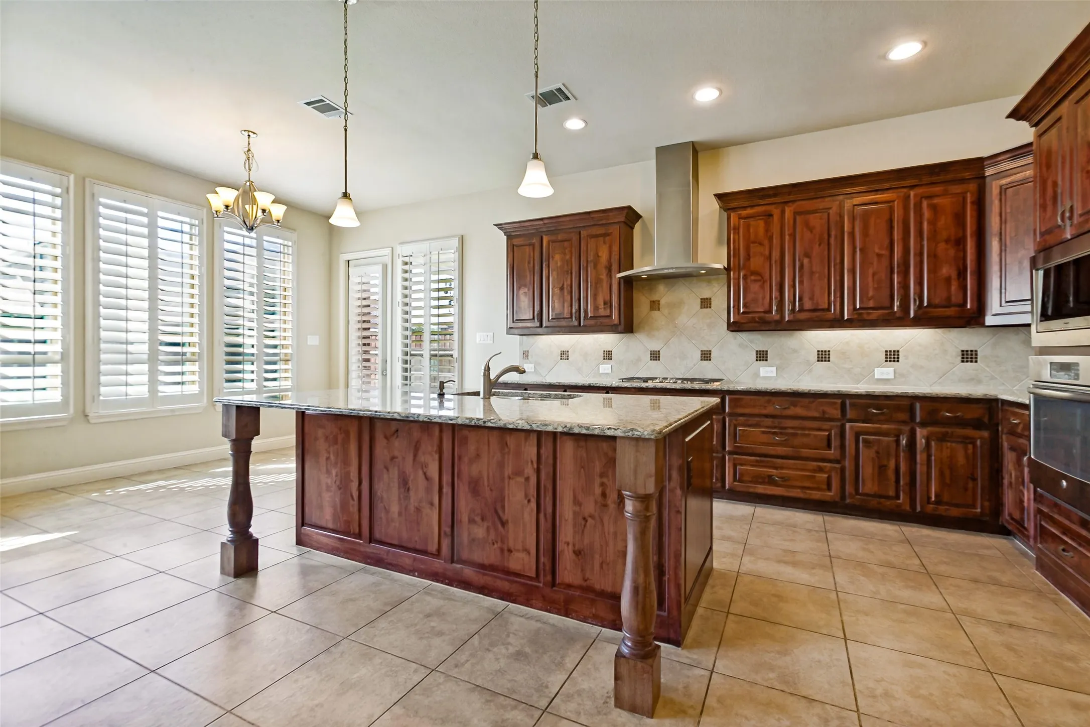 Kitchen featuring a central island with a stone countertop, rich wood cabinetry, stainless steel appliances, and tile flooring