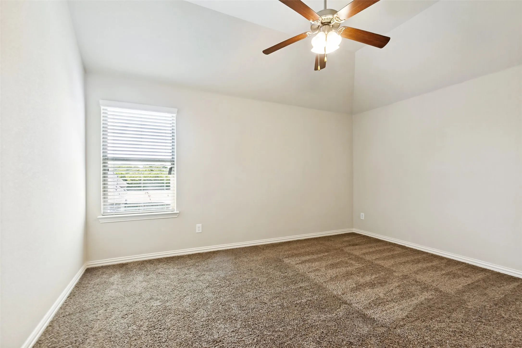 Vaulted ceiling with a ceiling fan and light fixture, window with blinds, and neutral carpet flooring