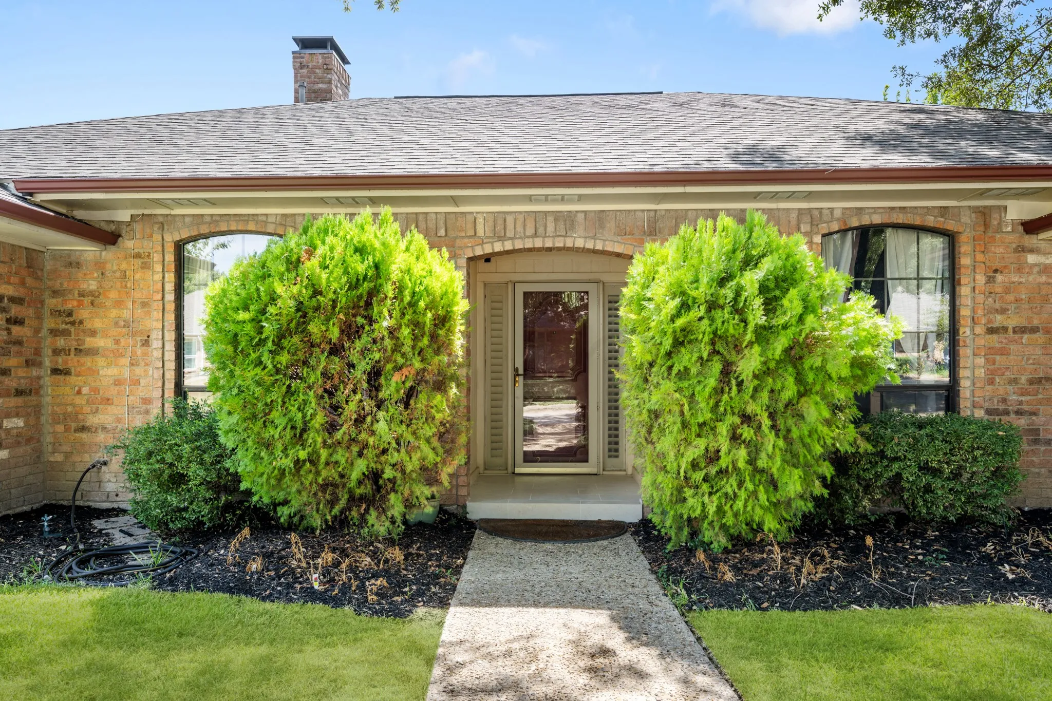 Charming front entry highlighted by classic brick detailing, mature manicured shrubs, and thoughtfully landscaped flower beds. A welcoming walkway leads to the inviting entry, creating a polished and well-maintained first impression.