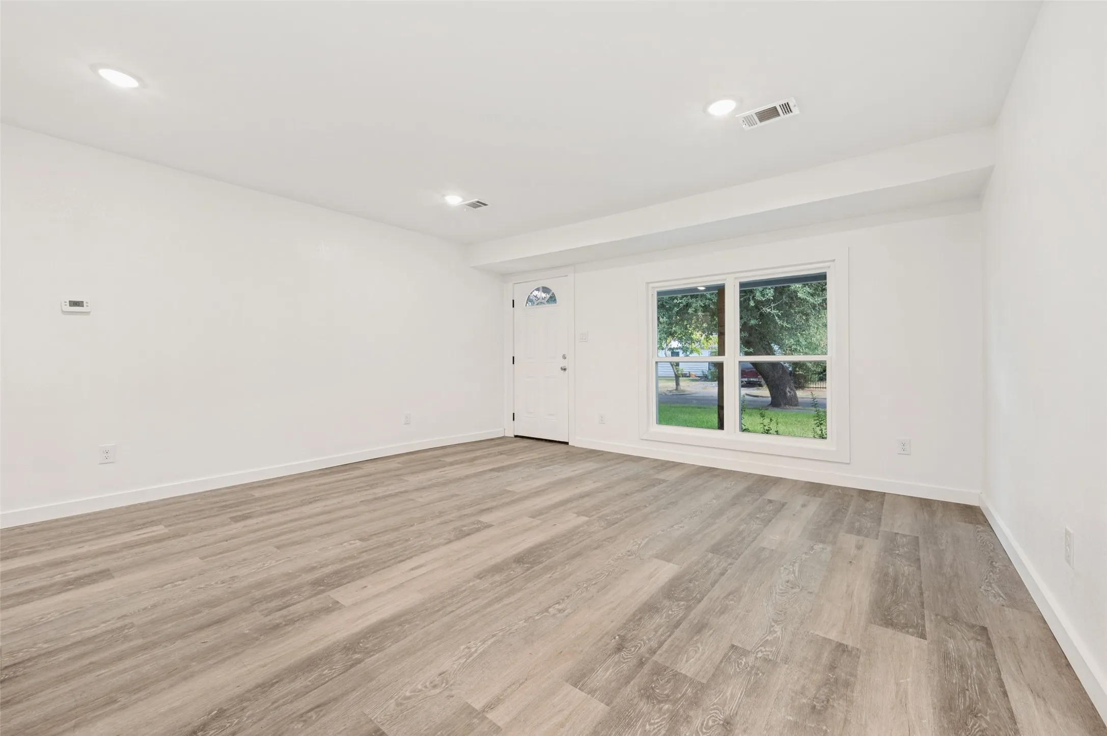 Spacious interior featuring wood-finish flooring, recessed lighting, and white walls