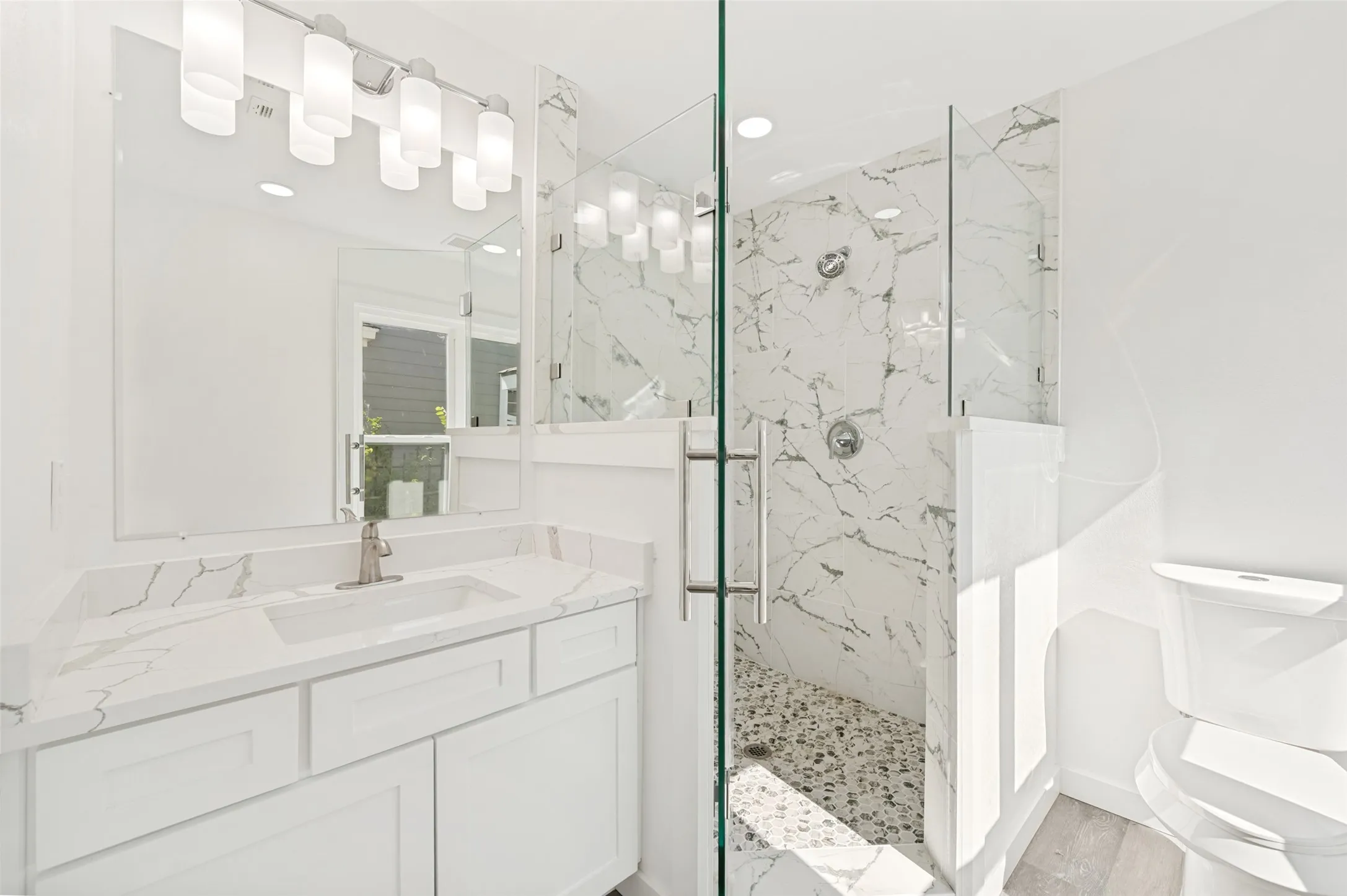 White vanity with a rectangular undermount sink and stone-finish countertop