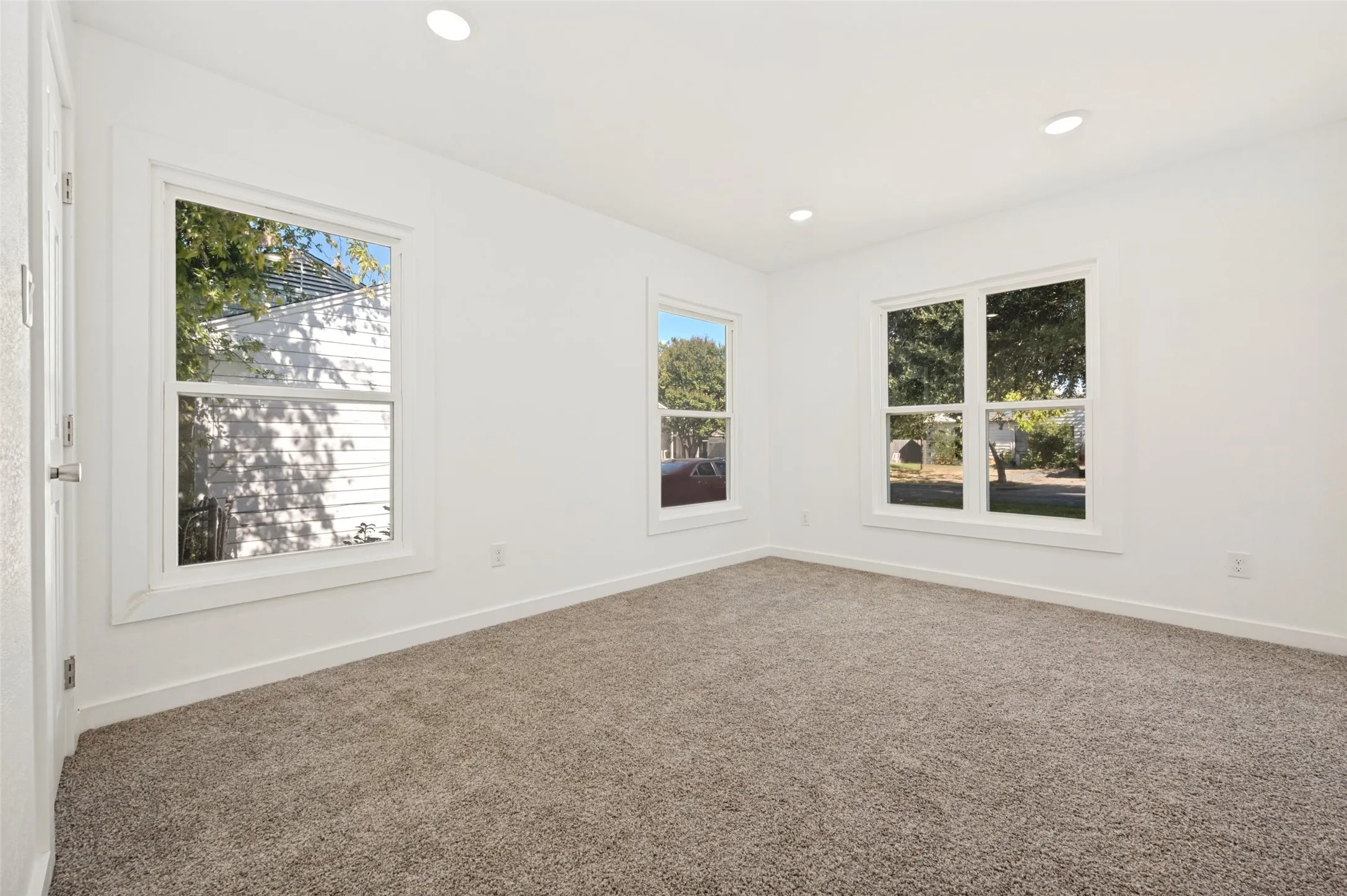 Plush carpet flooring, recessed lighting, and multiple windows with white trim