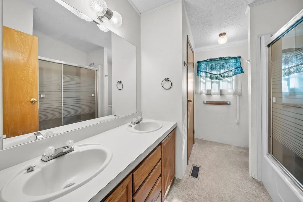 Dual vanity with white countertops, wood-finish cabinetry, and a mirrored wall
