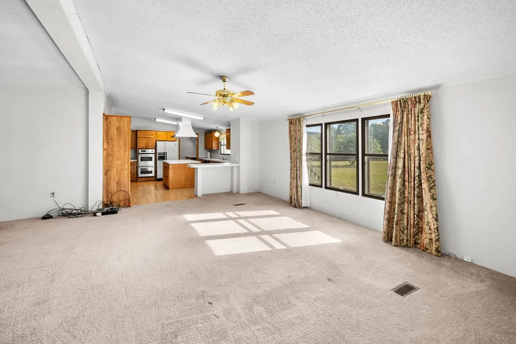 Open-concept living area with carpet flooring and ceiling fan