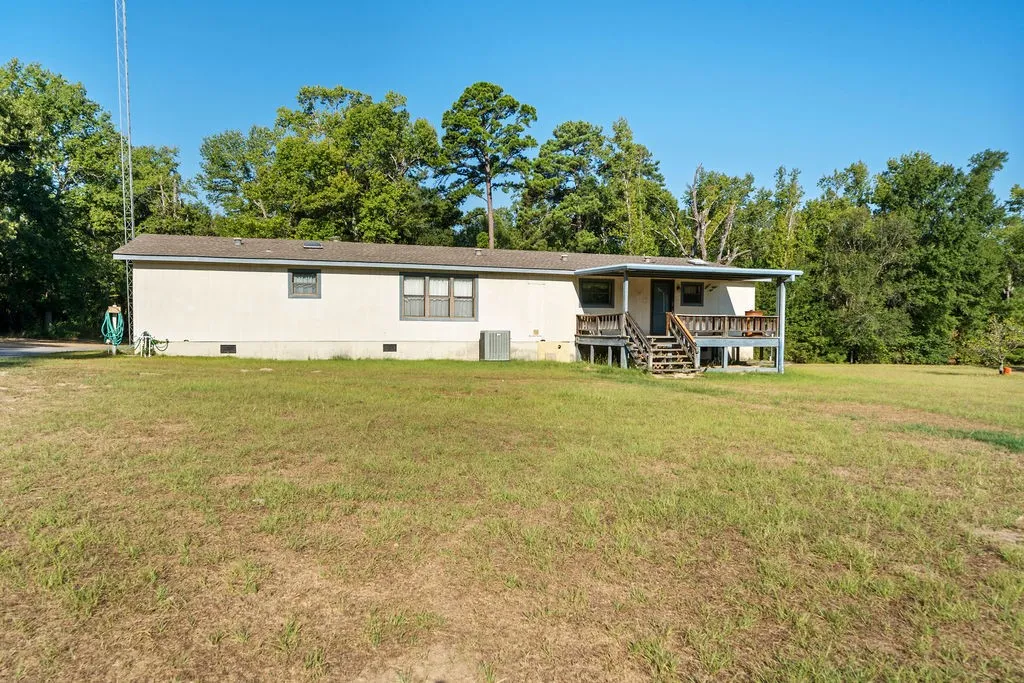 Expansive outdoor space featuring a covered porch with railings and stairs, providing direct access to the interior