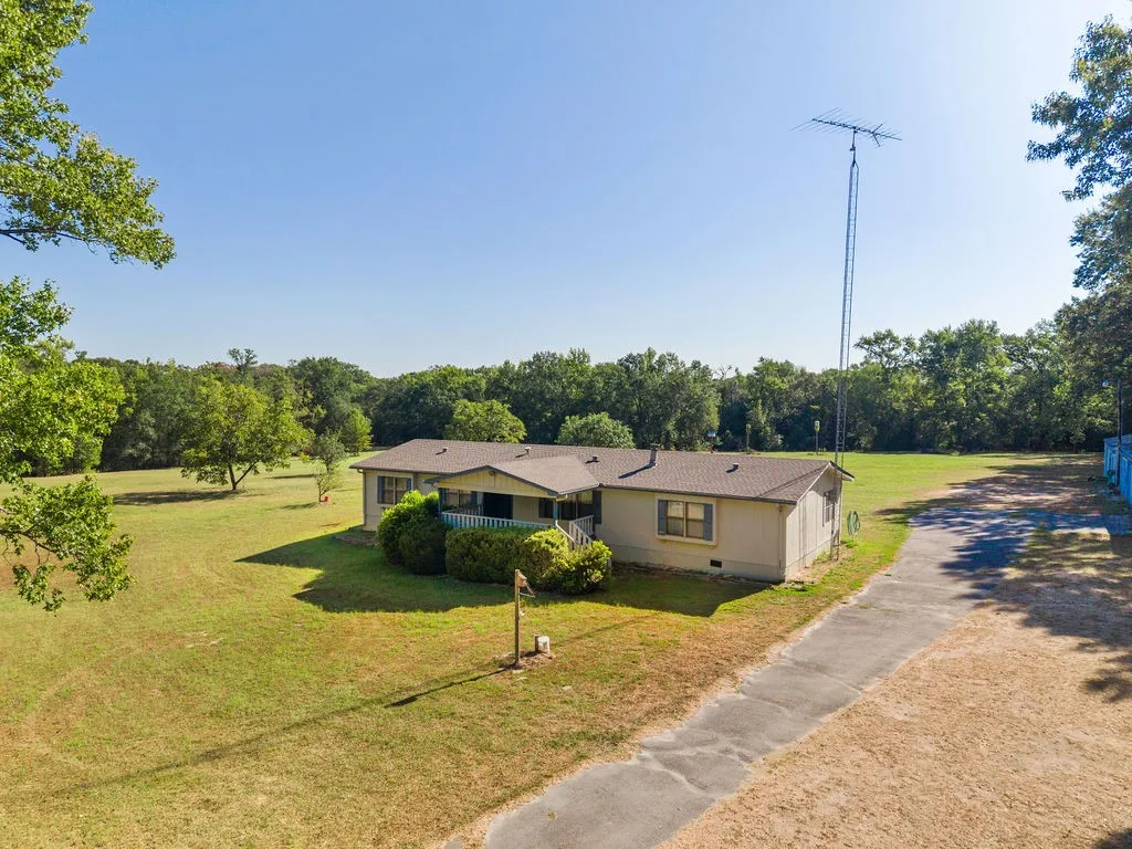 Expansive lot featuring a single-story residence with a covered porch and surrounding green space
