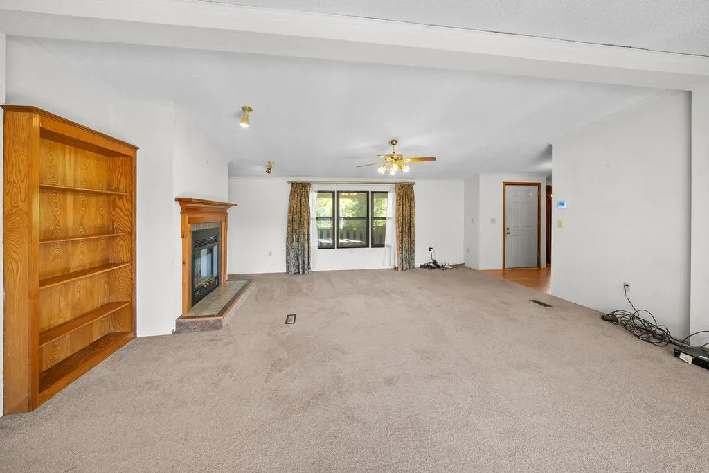 Recessed fireplace with hearth, built-in shelving, ceiling fan, and large window