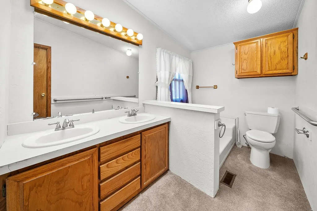 Double vanity with integrated sinks, wood-finish cabinetry, and a full-width mirror