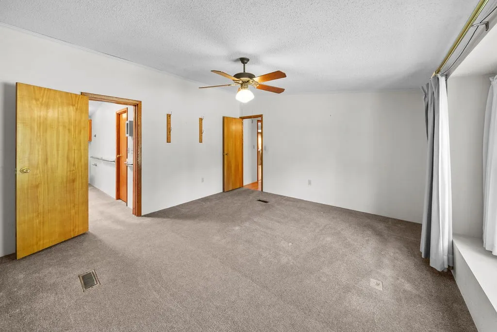 Neutral tone wall finishes, ceiling fan with integrated lighting, wood-finish interior doors, and carpeted flooring