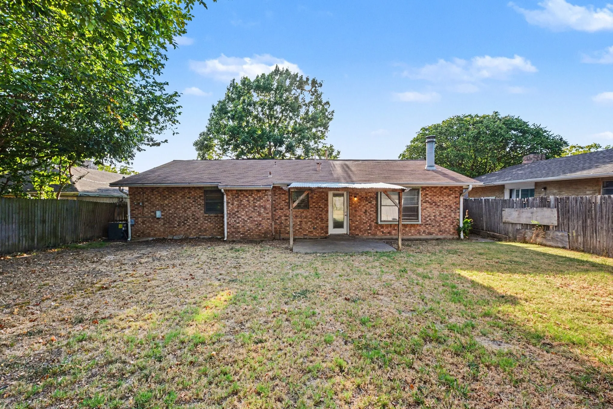 Brick exterior with a covered patio and a fenced backyard