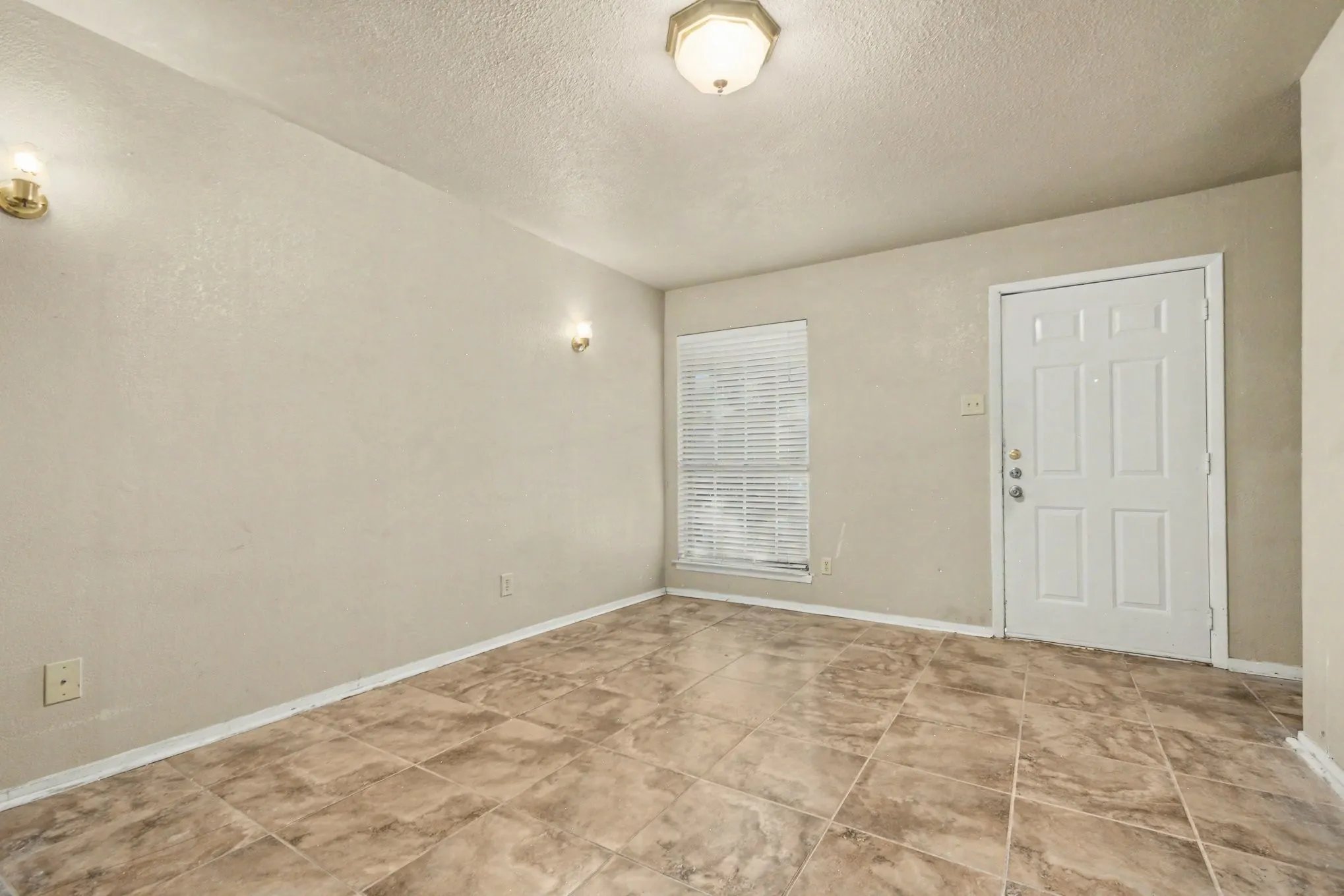 Ceramic tile flooring, neutral wall tones, window with horizontal blinds, flush mount ceiling light, and wall sconces