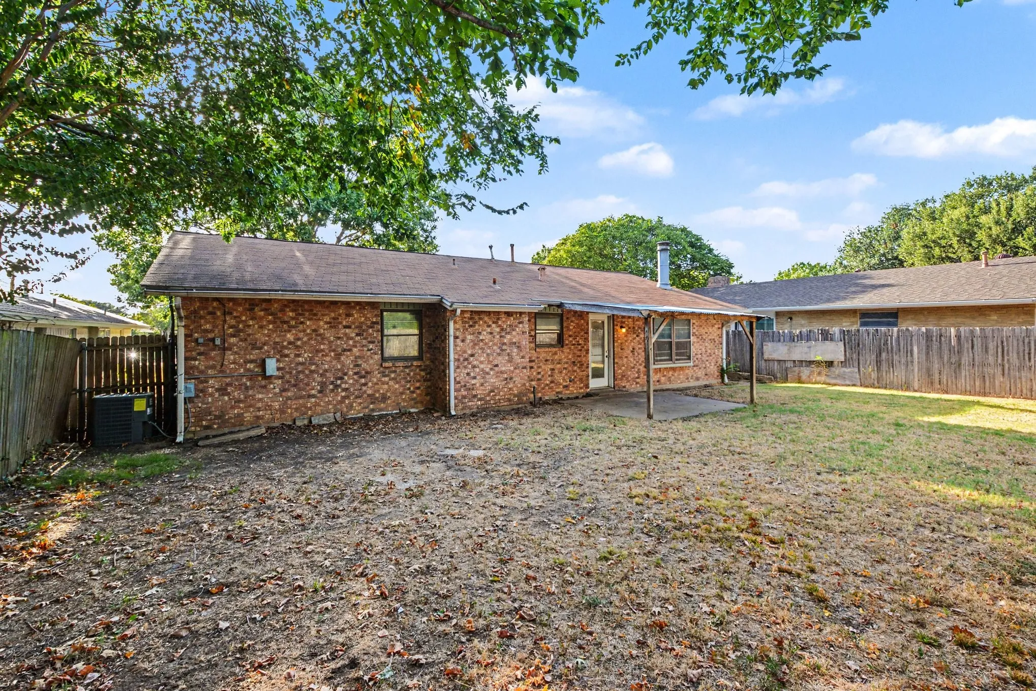 Expansive backyard featuring a brick exterior and a covered patio area