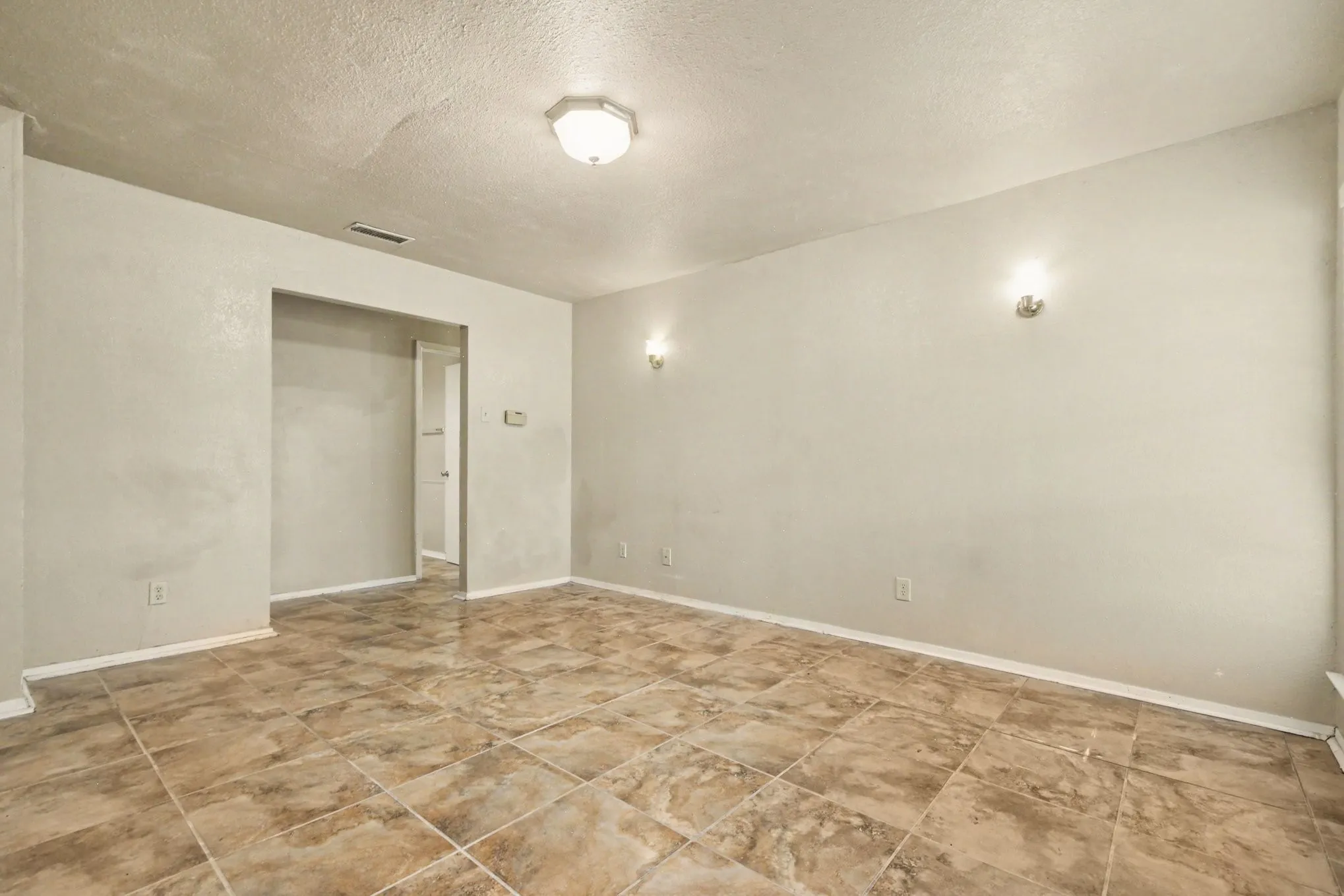 Recessed ceiling light, wall sconces, neutral wall tones, tiled flooring, open doorway