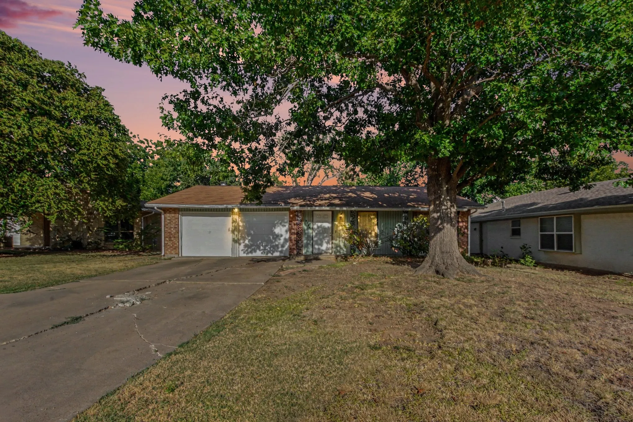 Brick facade with double garage doors, and a mature tree