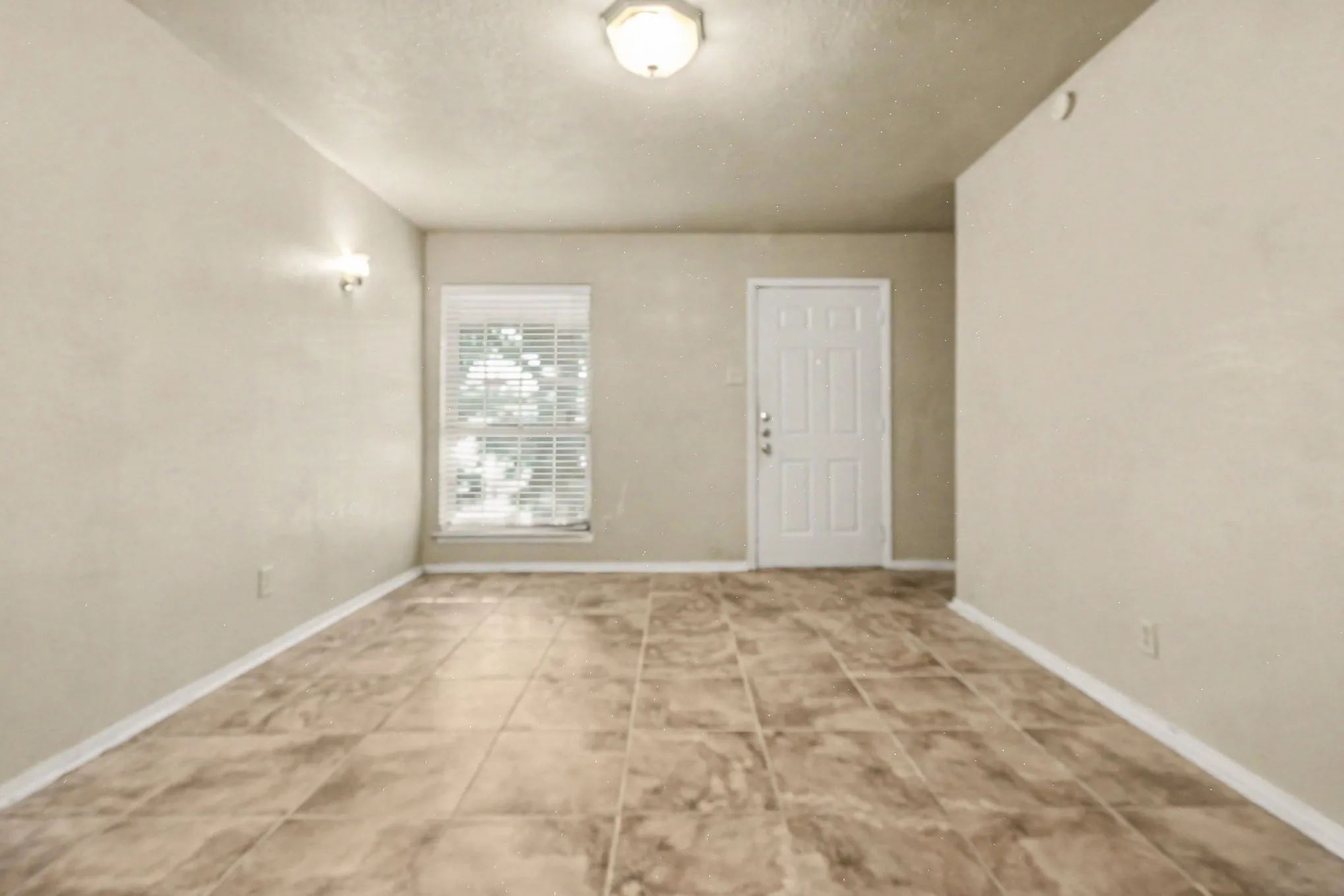 Tile flooring, flush mount ceiling light, single window with blinds, wall sconce, paneled door
