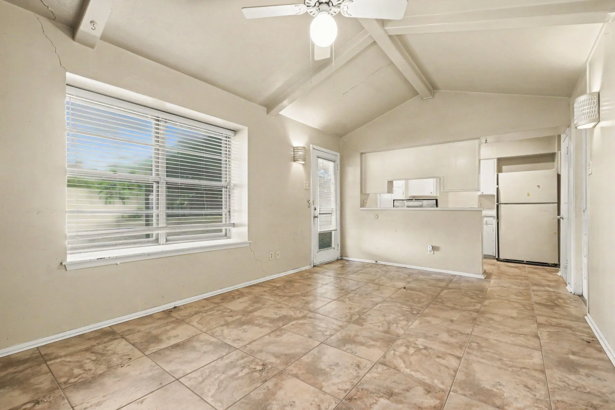 Vaulted ceiling with exposed beams, ceiling fan, and tiled flooring