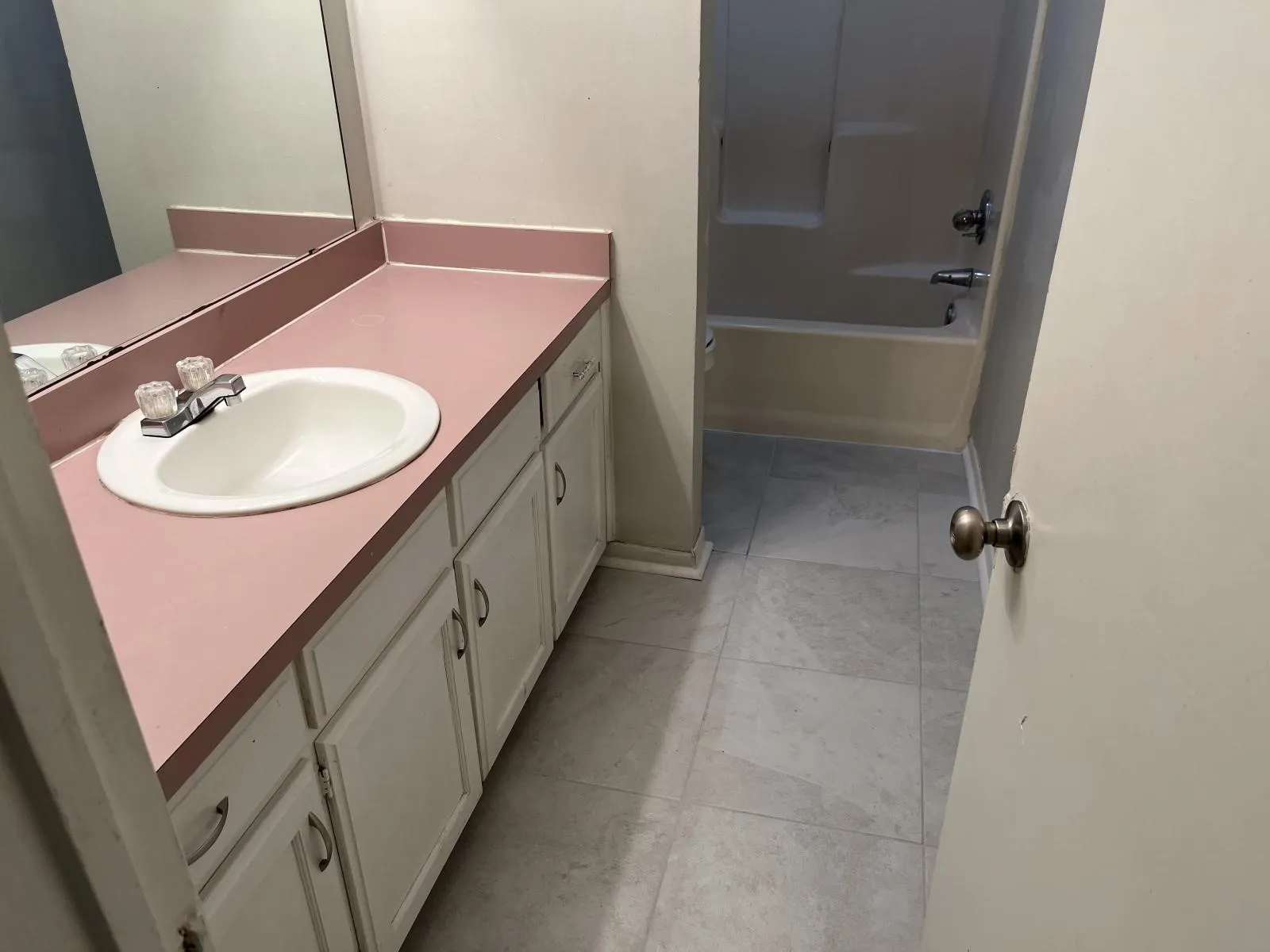 Bathroom vanity with an integrated sink, dual mirrors, white cabinetry, and gray tile flooring