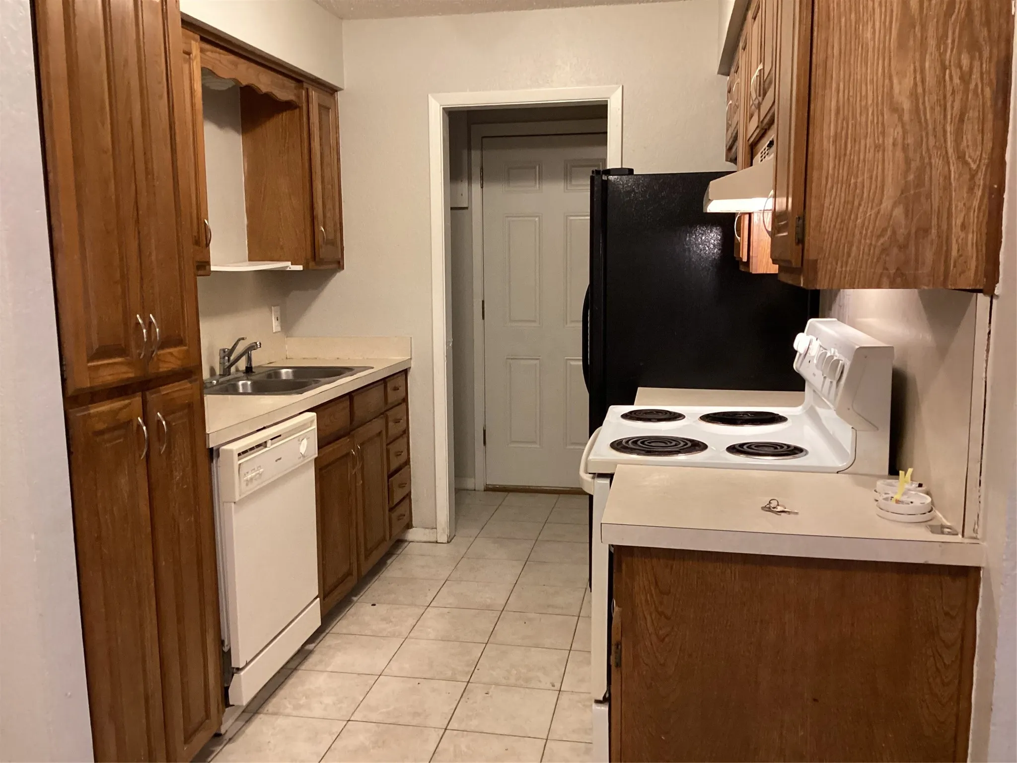 Kitchen featuring wood-finish cabinetry, tile flooring, and integrated white appliances