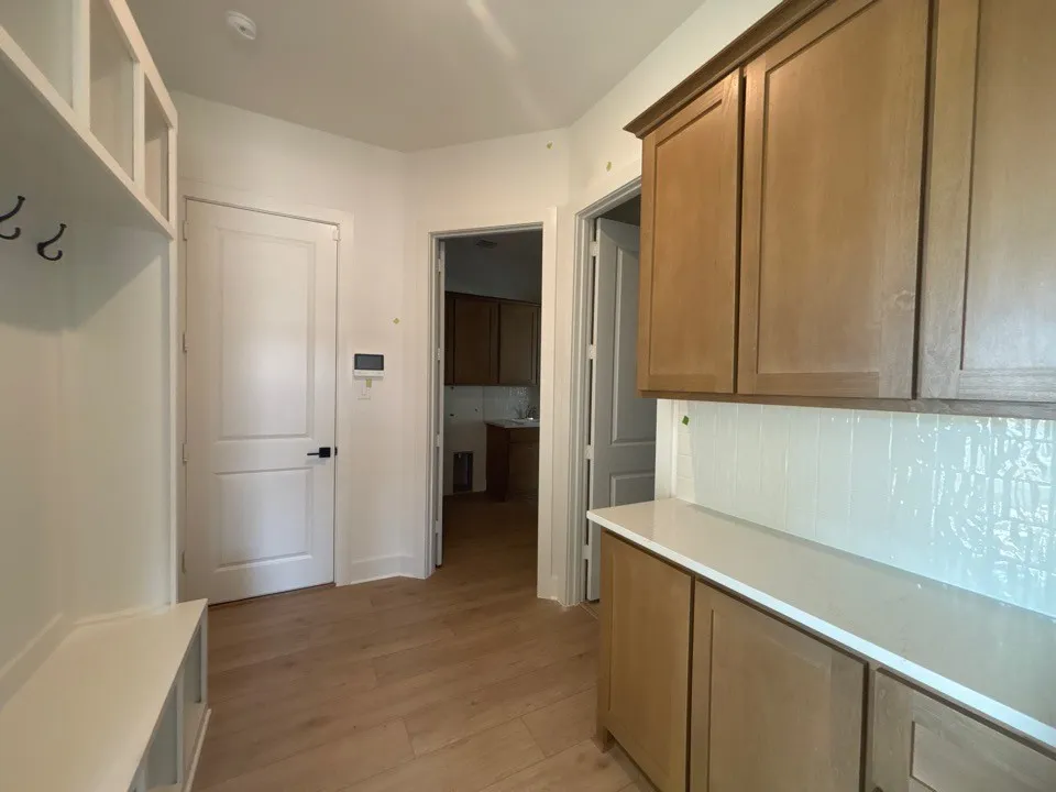 Built-in bench with storage, wood-finish flooring, white flat panel door, built-in cabinetry, and white countertop
