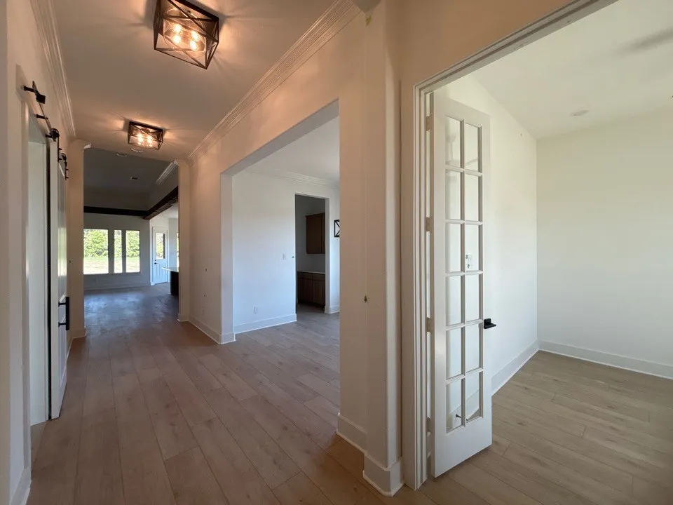 Light wood-finish flooring throughout, white trim, recessed lighting, and French doors