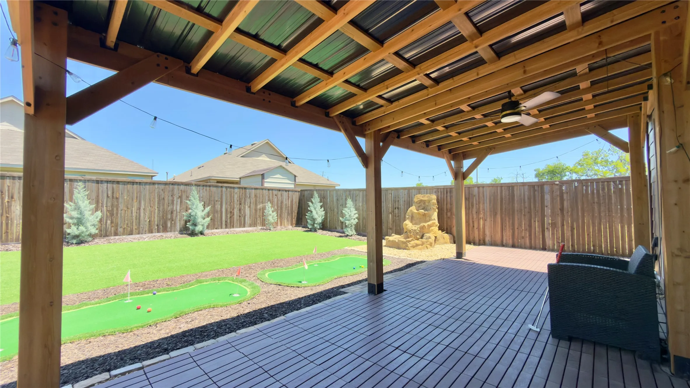 Expansive covered patio featuring a wood-beam ceiling with a ceiling fan and string lighting