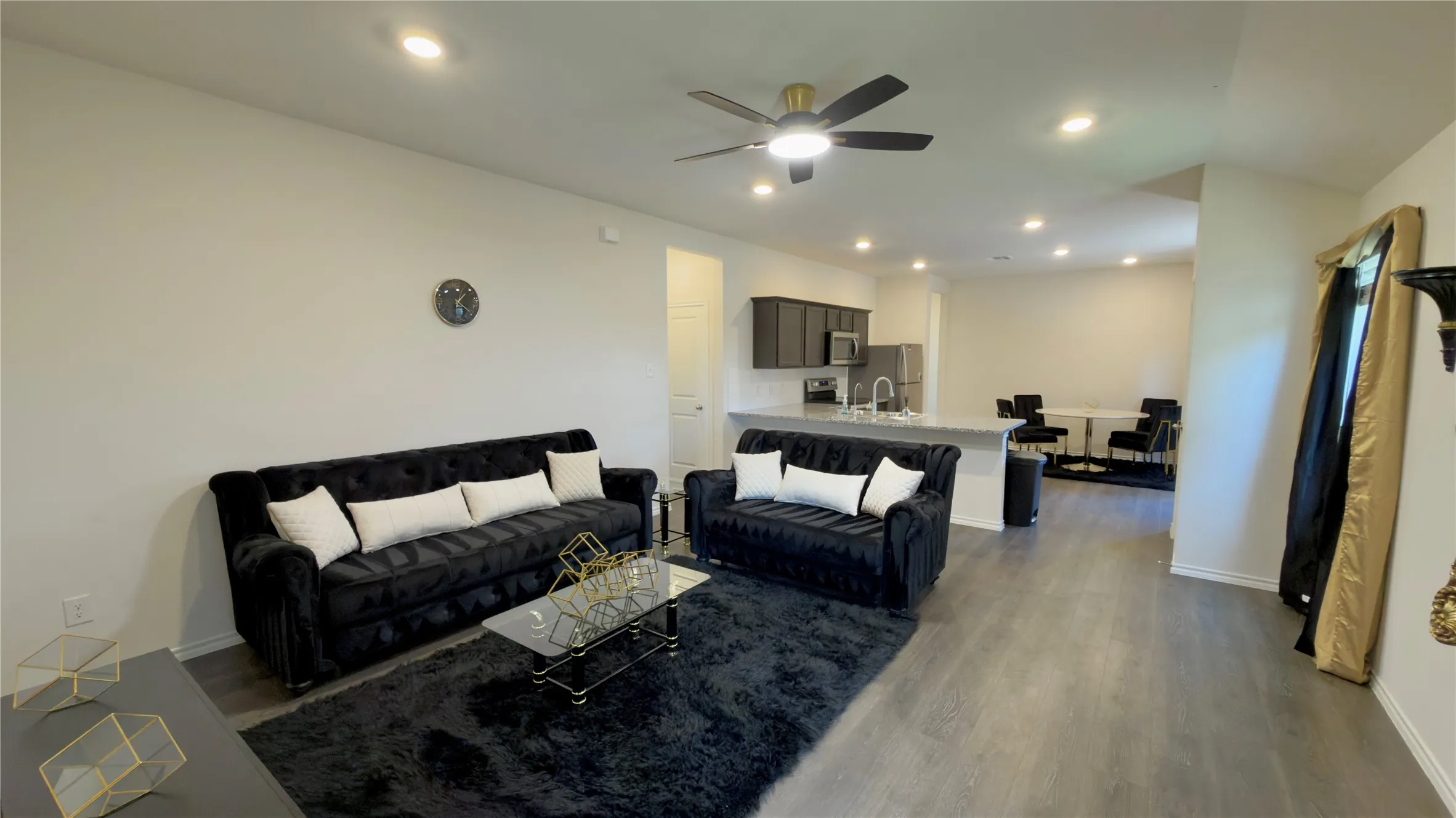 Spacious open-concept living area featuring wood-finish flooring, recessed lighting, and a ceiling fan