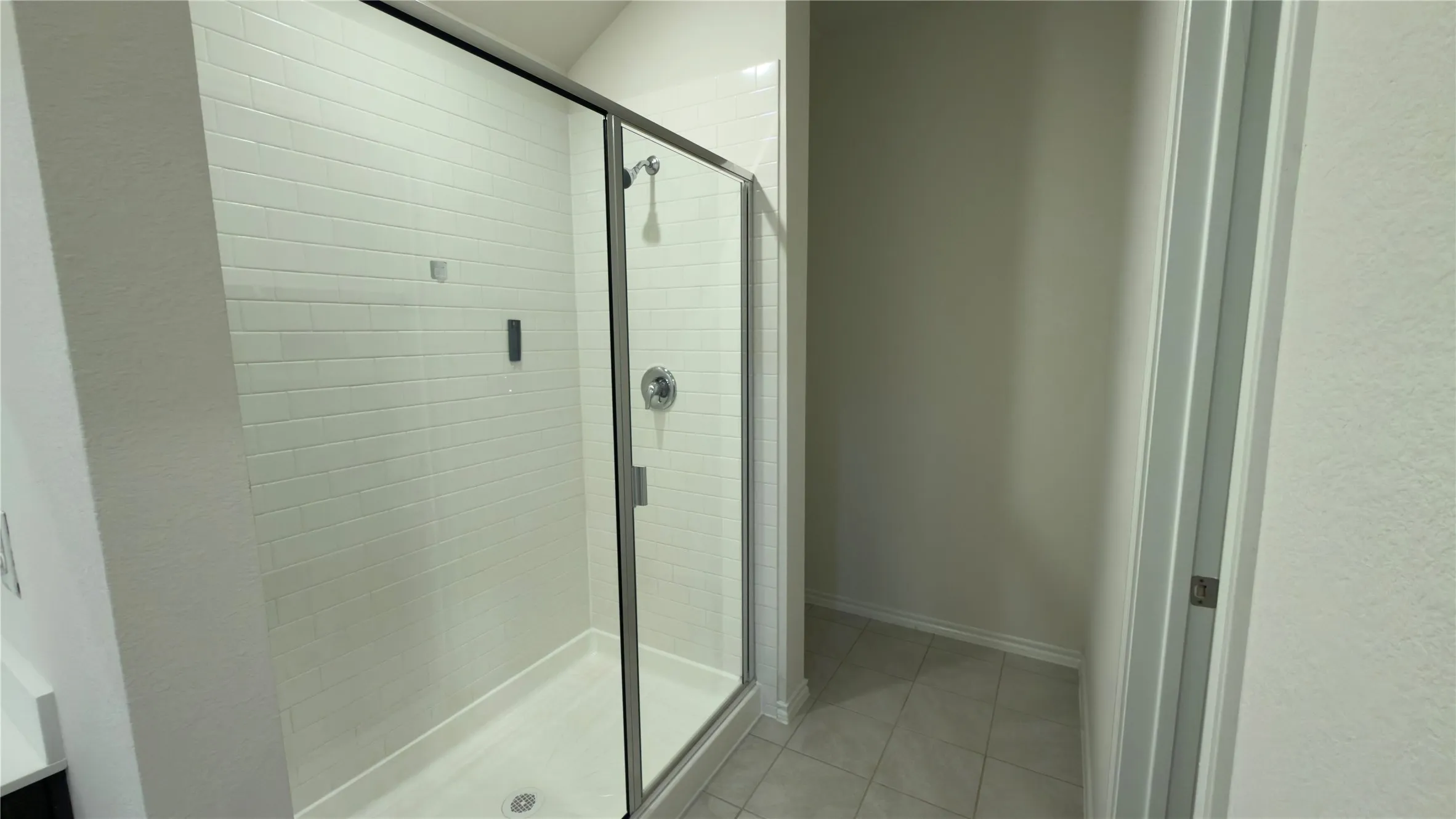 Glass-enclosed shower with subway tile surround, chrome fixtures, and a white shower pan