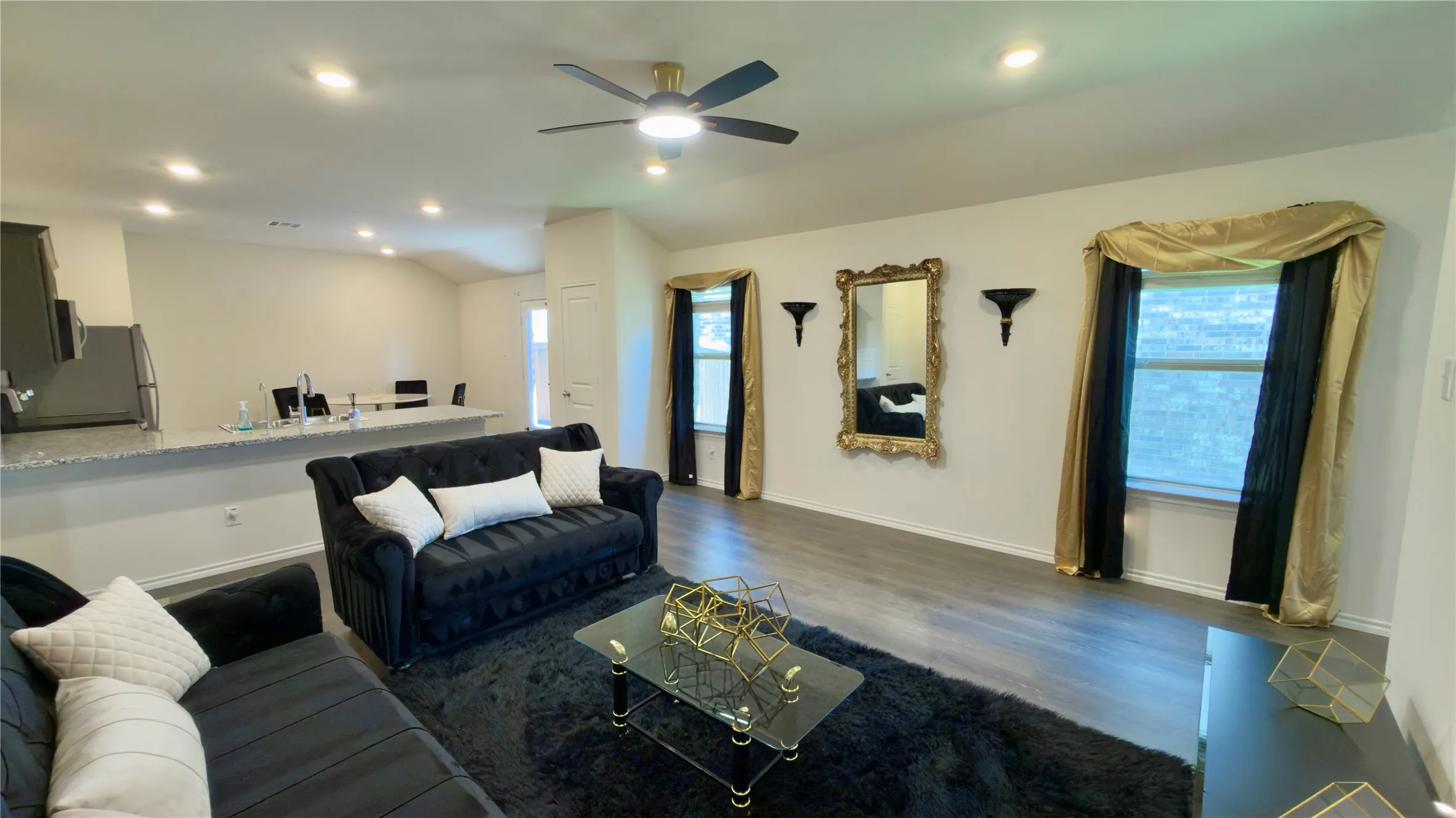 Open-concept living area with wood-finish flooring, a contemporary ceiling fan, recessed lighting, and a breakfast bar featuring a light-colored countertop