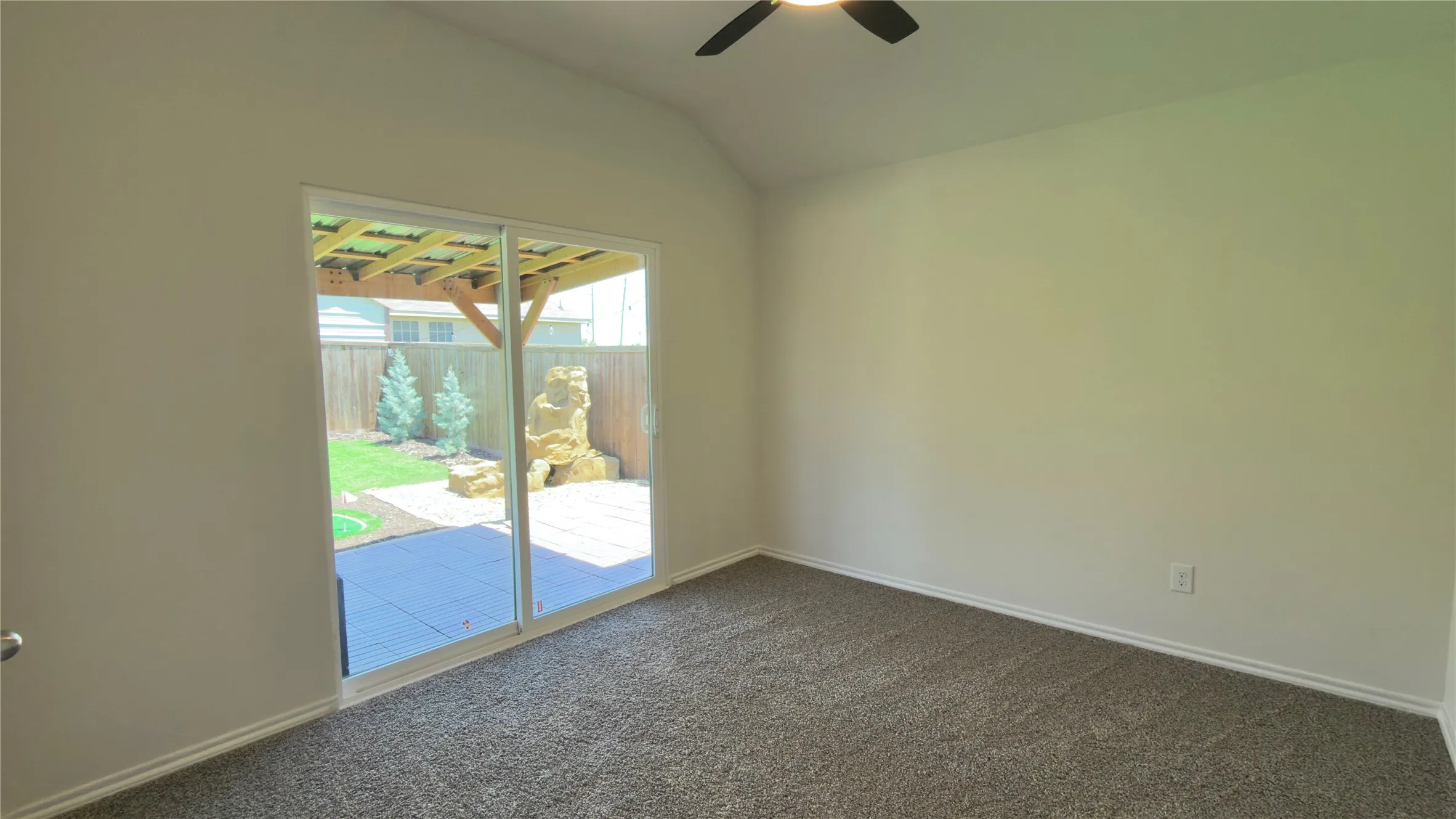 Sliding glass door opening to a paved patio and landscaped backyard