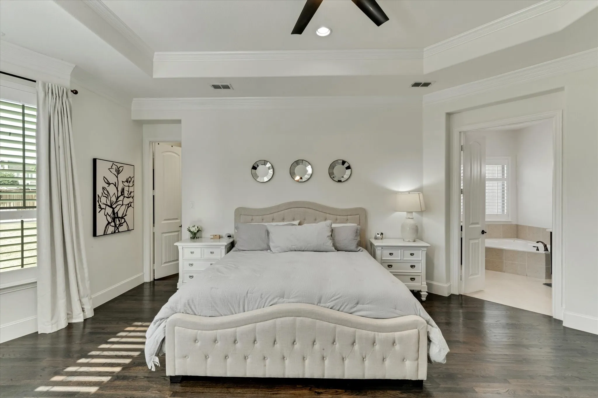 Tray ceiling with recessed lighting, dark wood-finish flooring, white trim, and window with white shutters