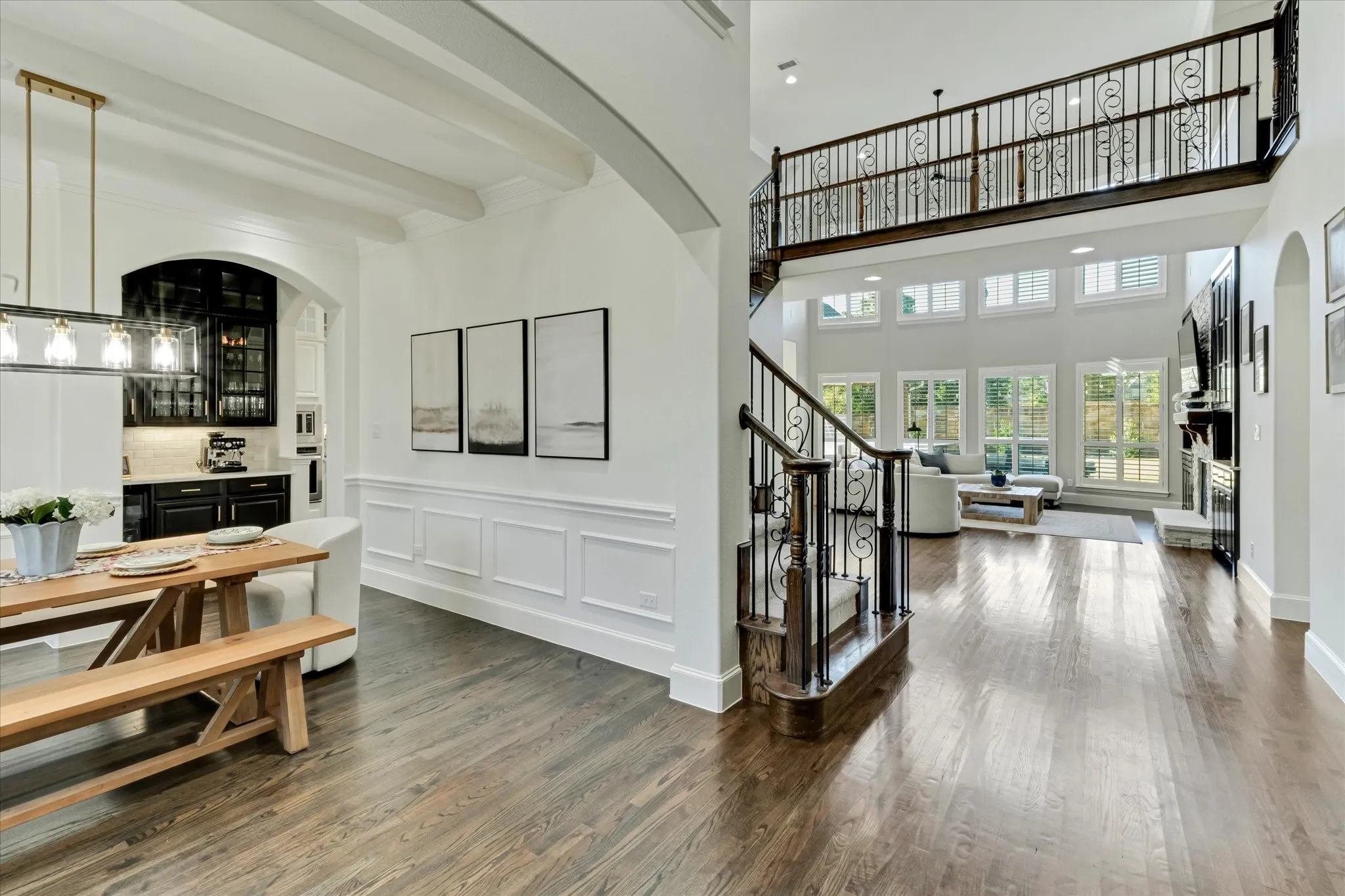 Wood-finish flooring throughout, with a grand staircase featuring ornamental iron balusters