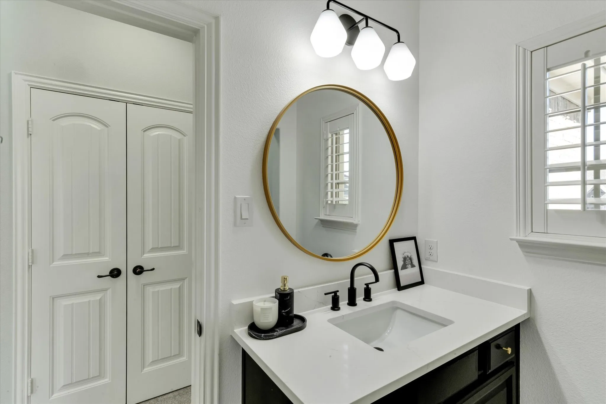 Vanity with an undermount sink, a white countertop, and a matte black faucet