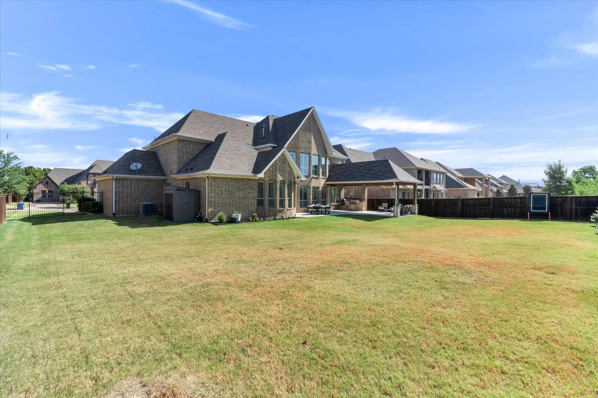 Expansive backyard with a covered patio, built-in outdoor kitchen, and privacy fencing