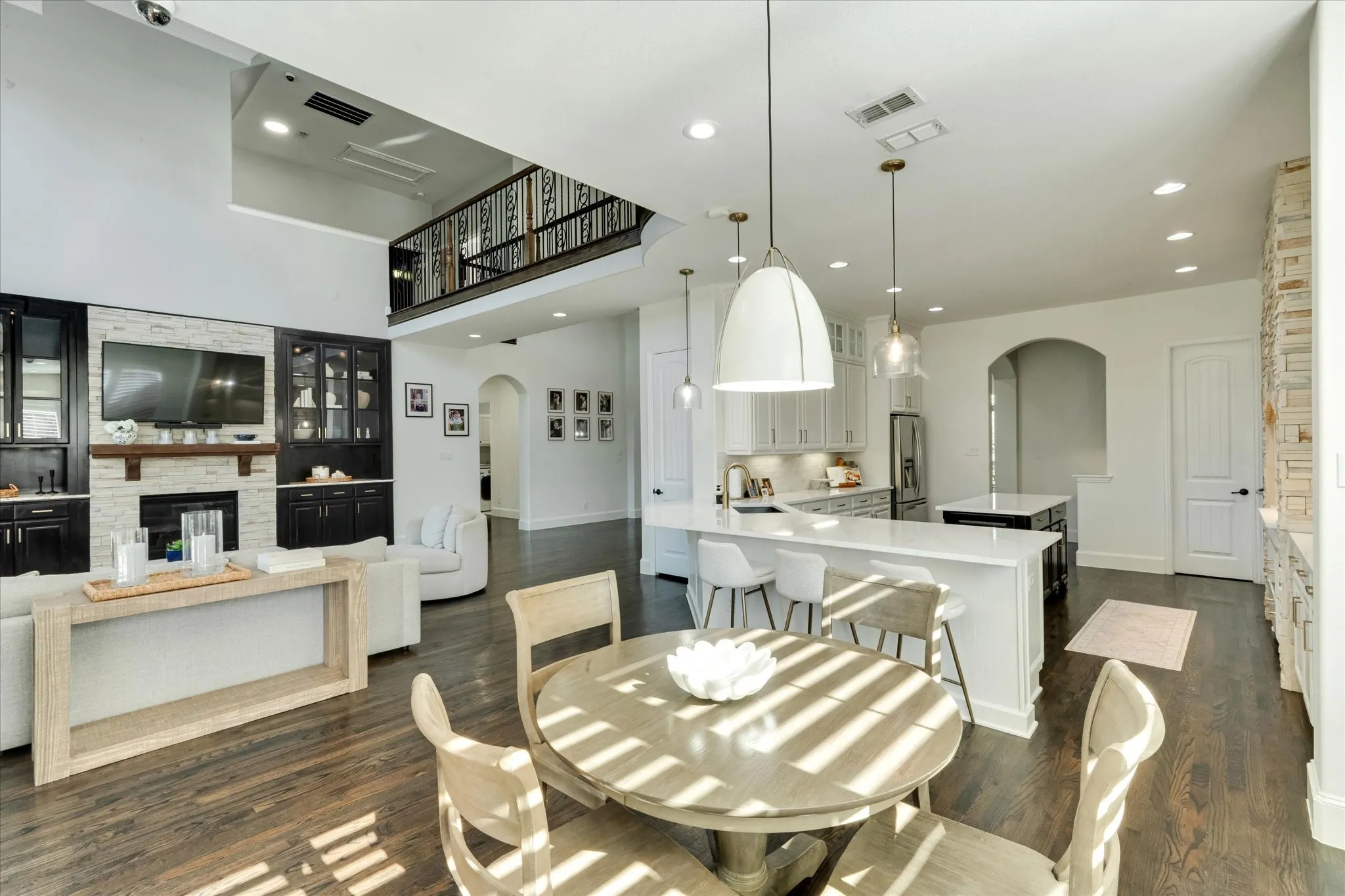 Open-concept living area with dark wood-finish flooring, a two-story ceiling, and a kitchen island with seating