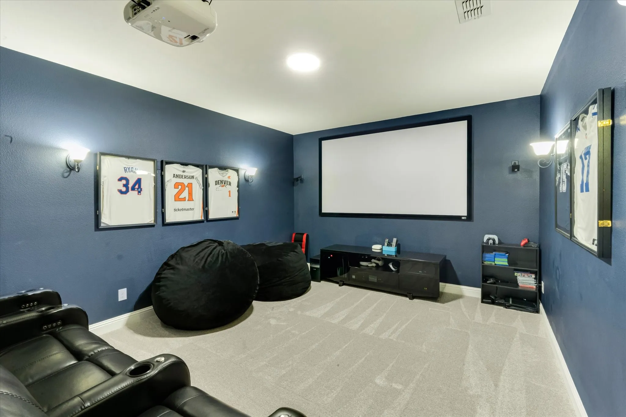 Projector screen with recessed lighting, wall-mounted sconce lighting, and ceiling-mounted​​‌​​​​‌​​‌‌​‌‌​​​‌‌​‌​‌​‌​​​‌​​ projector