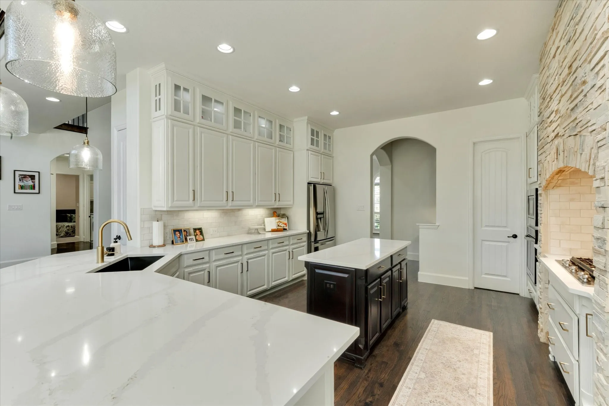 Gourmet kitchen with white cabinetry, built-in stainless steel appliances, and a central island with a contrasting dark base