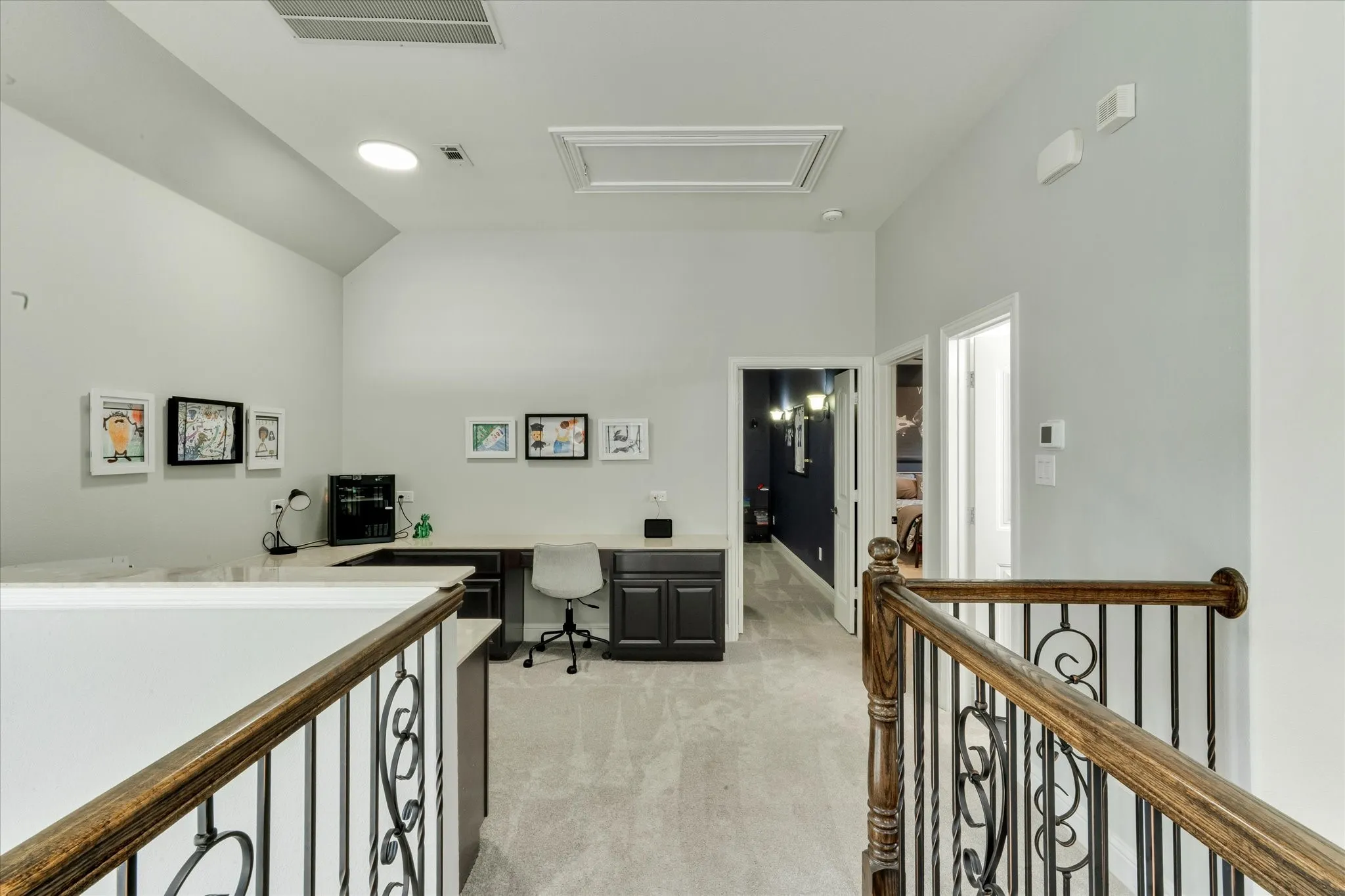 Loft area featuring vaulted ceilings, built-in desk cabinetry, and carpeted flooring