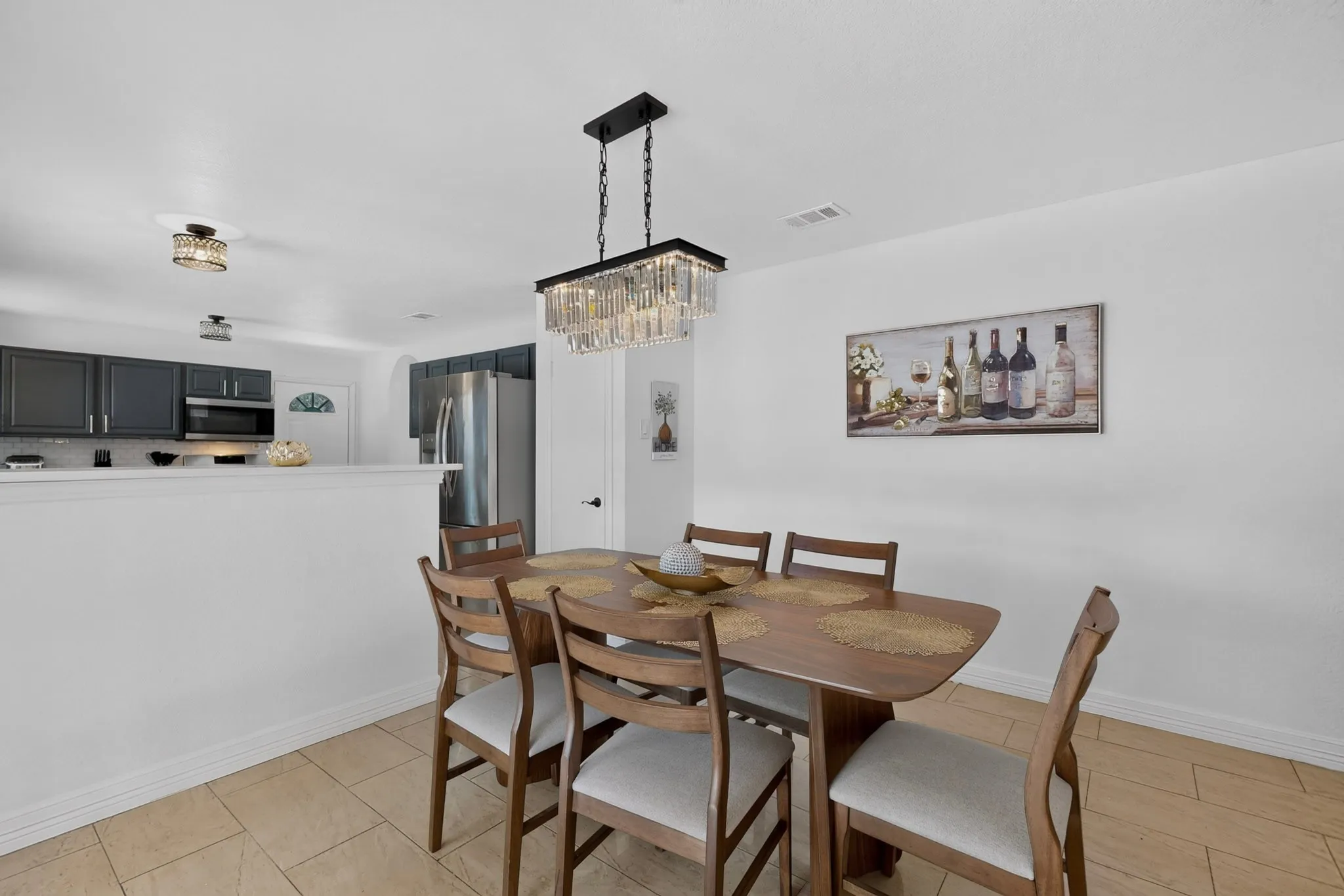 Dining area featuring a rectangular chandelier, tile flooring, and a half wall partition