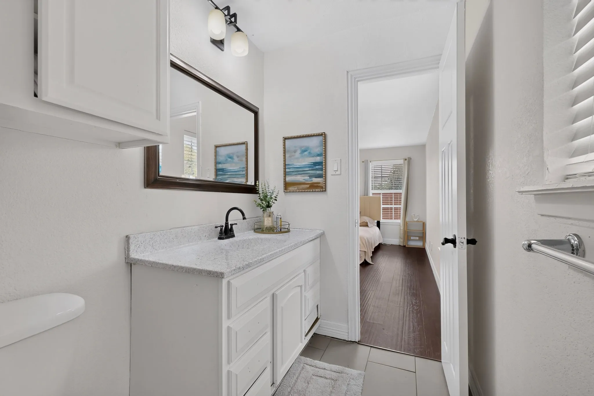 White vanity with a speckled countertop, undermount sink, and matte black faucet