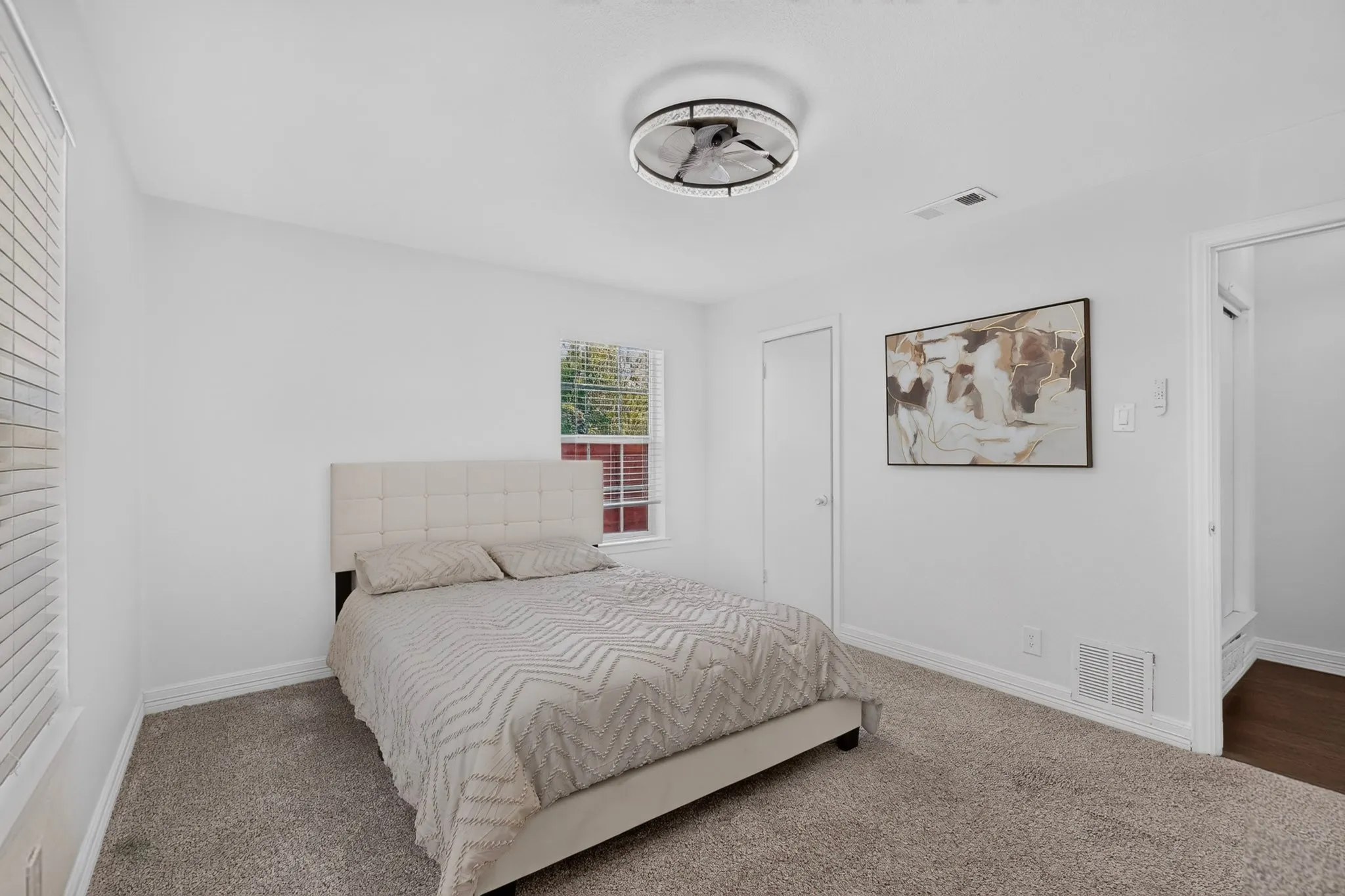 Carpeted flooring, white painted walls, ceiling-mounted light fixture, and a window with blinds