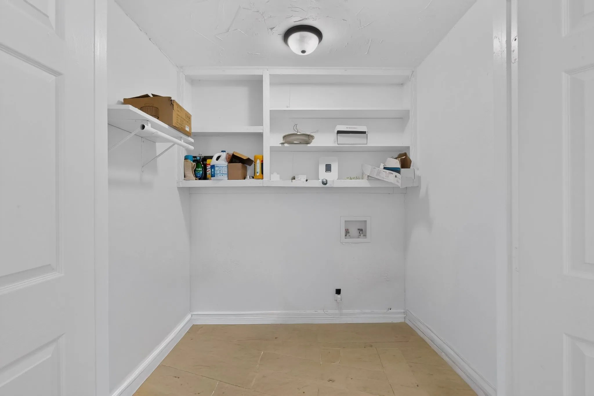 Utility room with built-in shelving, a wall-mounted flush light fixture, and tile flooring