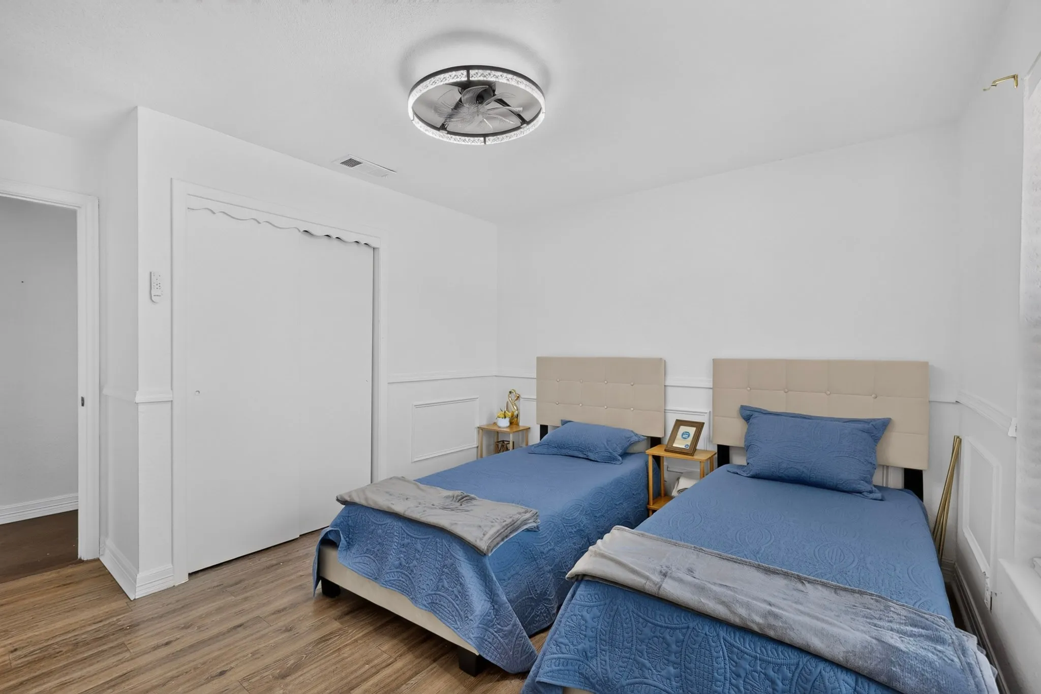Recessed lighting fixture, wood-finish flooring, white paneling on walls, white sliding closet door